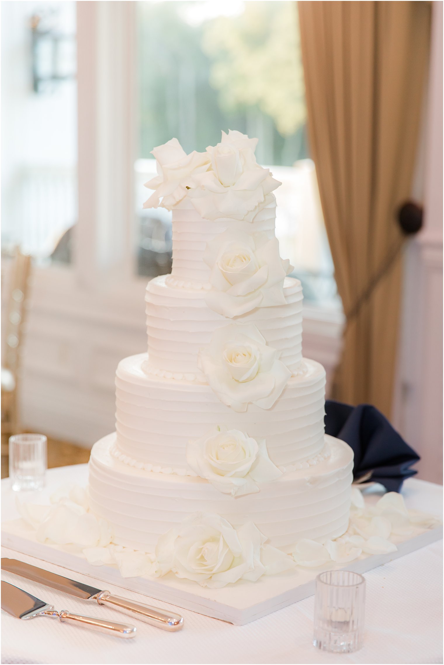 all-white tiered wedding cake with roses
