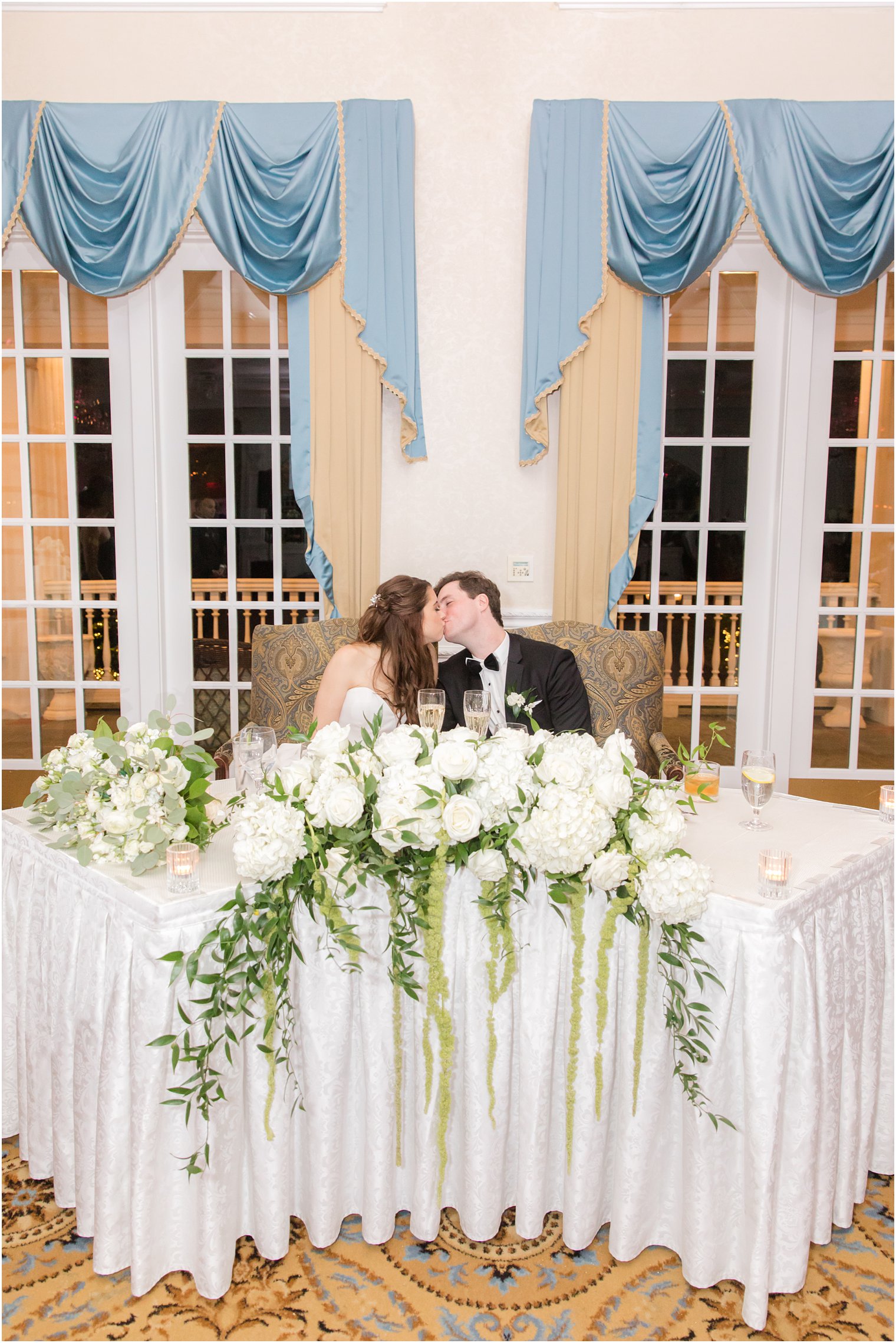 newlyweds kiss at sweetheart table at the Eagle Oaks Golf and Country Club