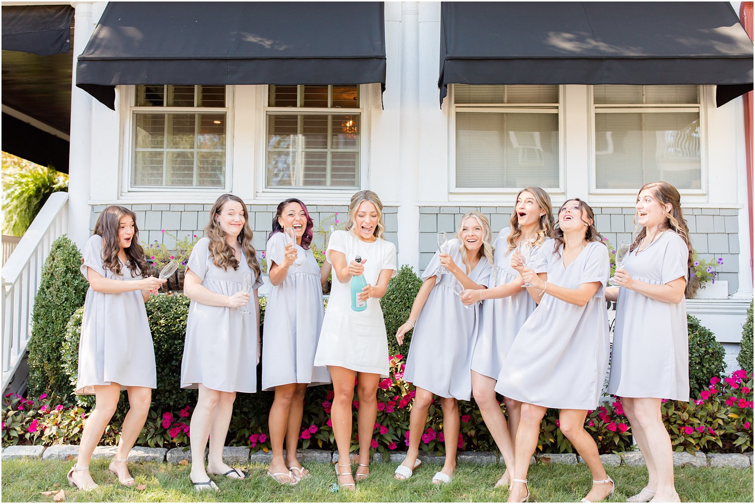 bride pops champagne bottle with bridesmaids