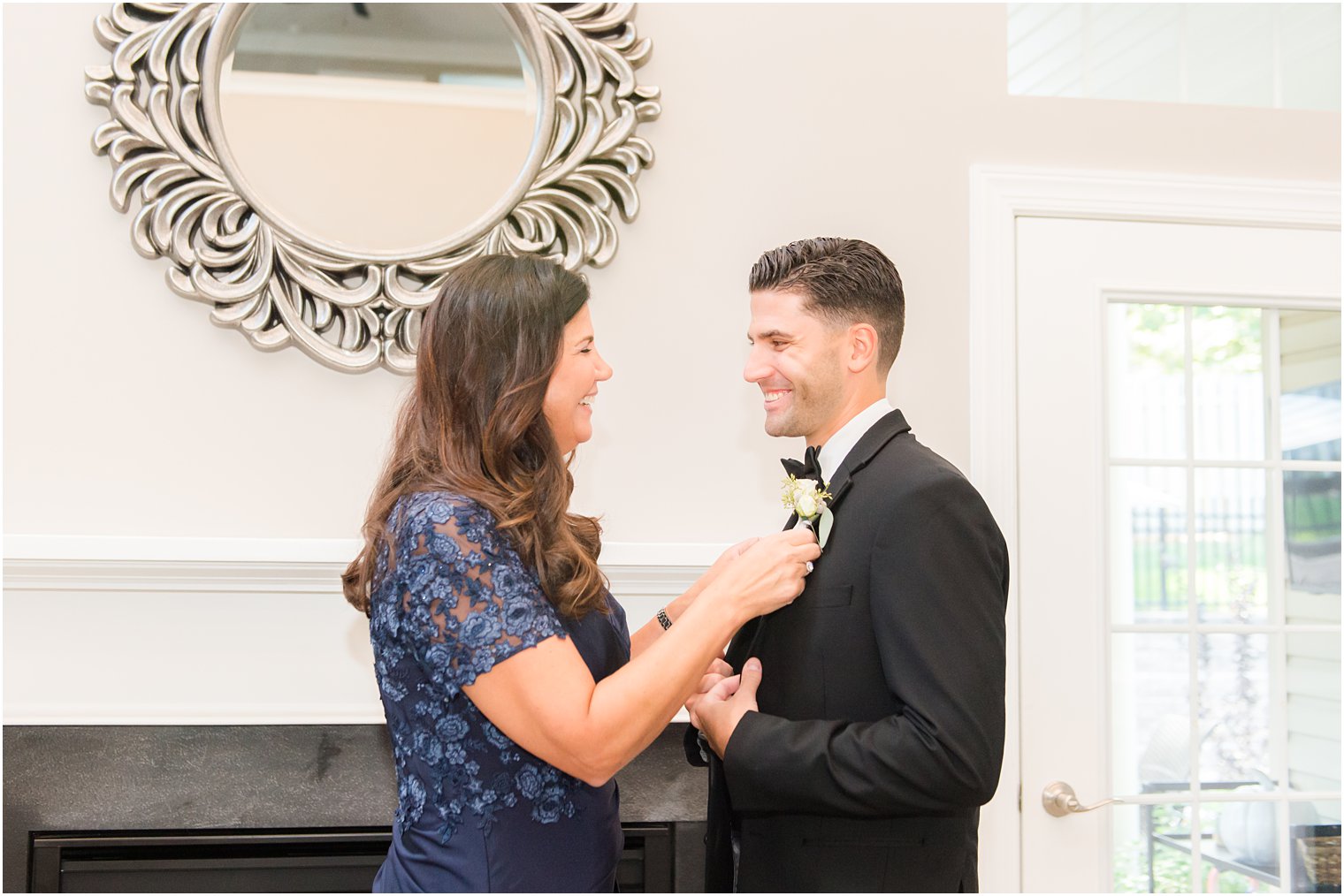 mom helps groom with boutonnière