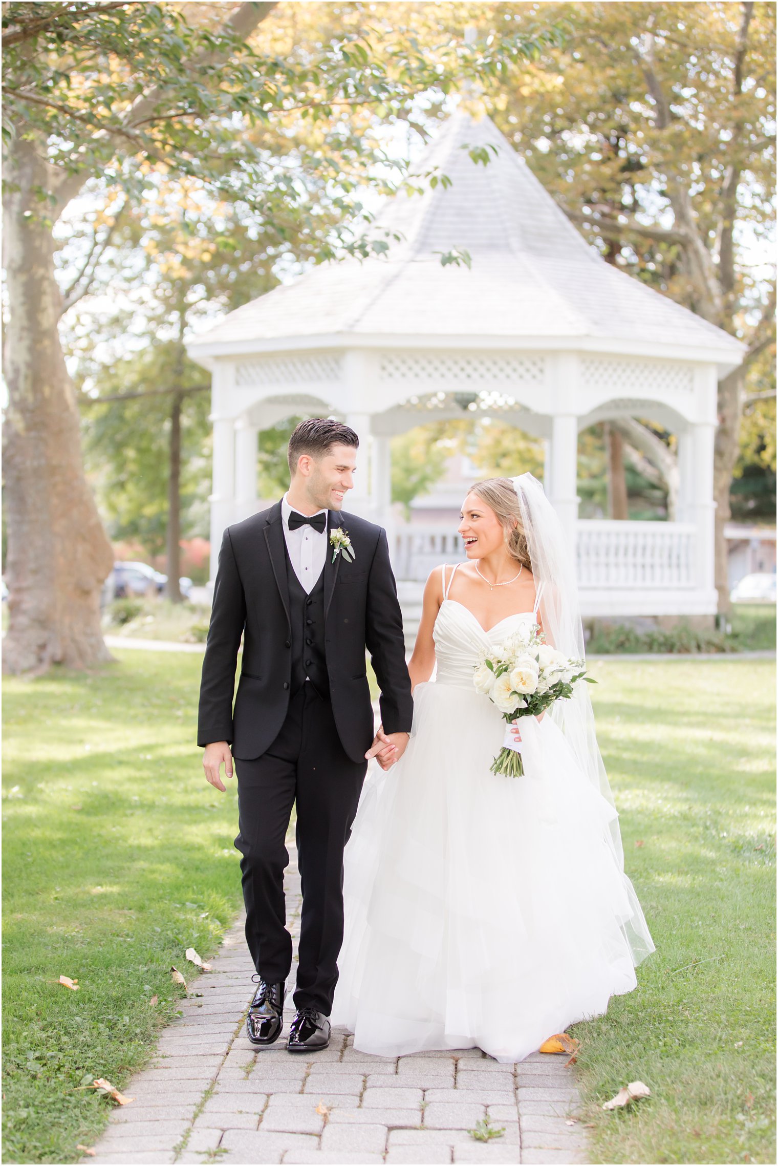 newlyweds walk by gazebo at the Mill Lakeside Manor