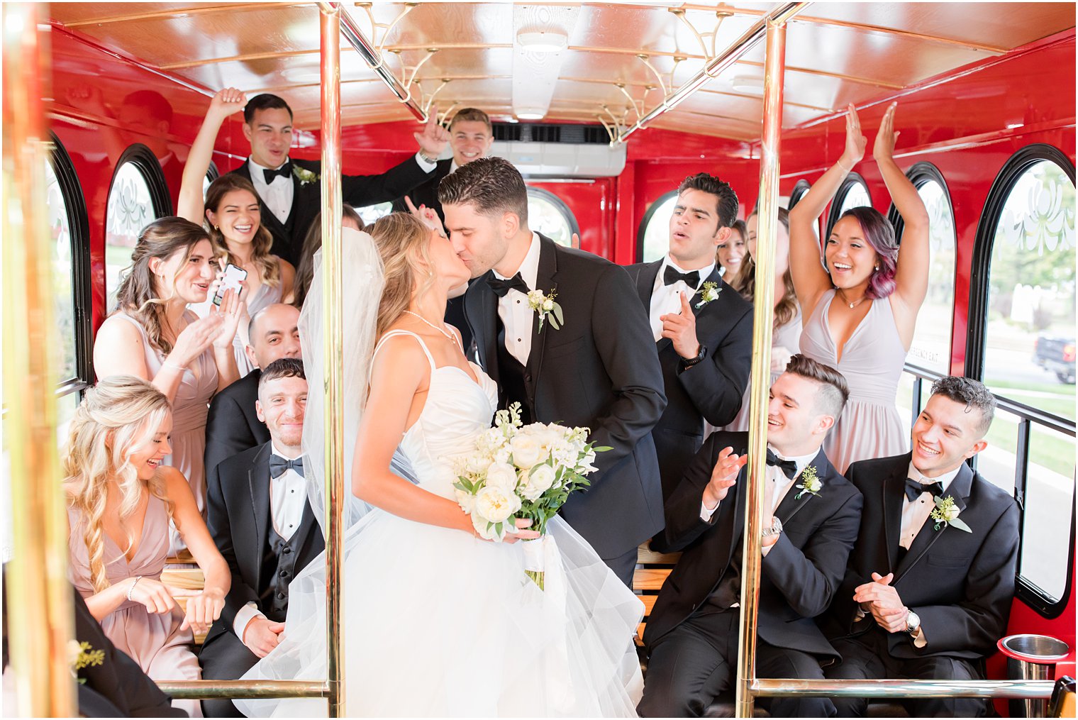 newlyweds kiss with wedding party cheering on trolley