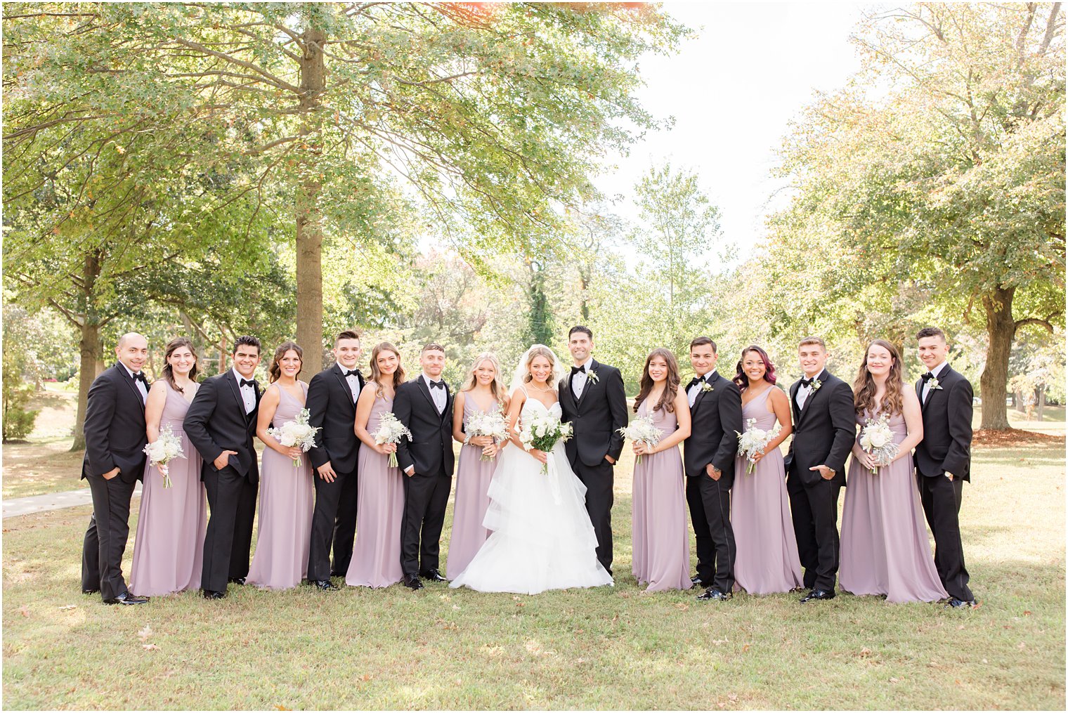 newlyweds pose with wedding party in black and purple