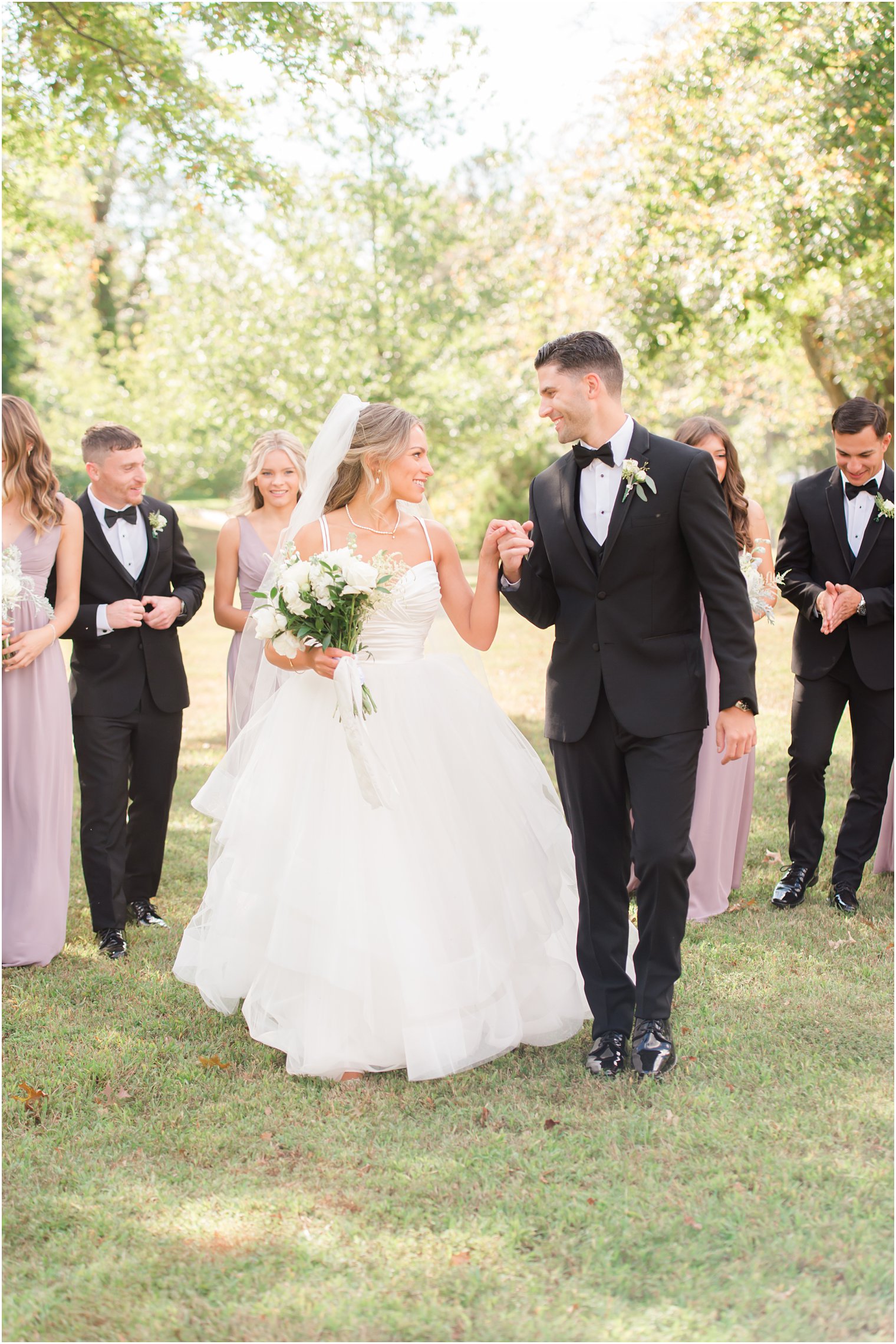 bride and groom walk with wedding party in Spring Lake NJ