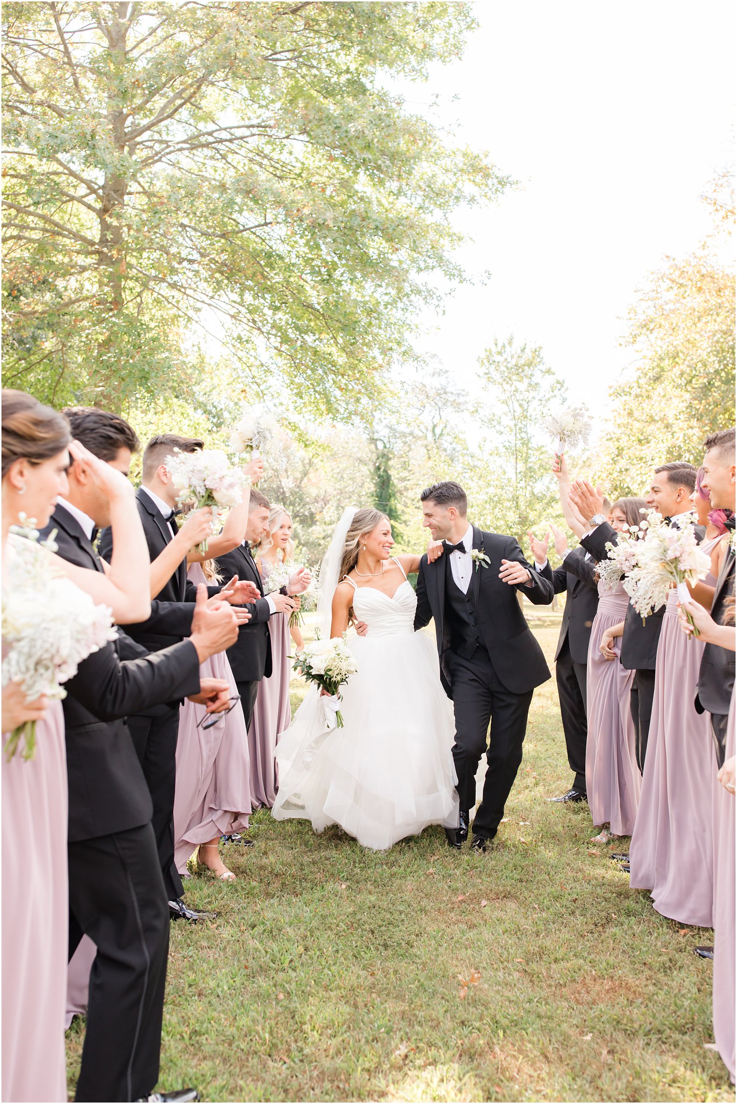 bride and groom walk between wedding party cheering