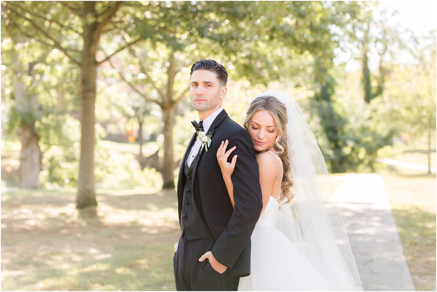 bride hugs groom from behind during wedding photos in Spring Lake NJ