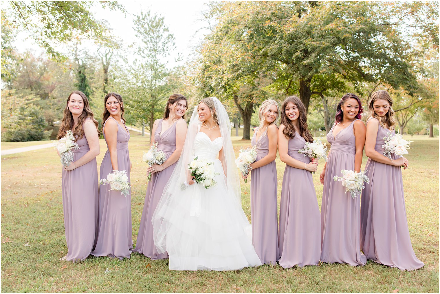 bride poses with bridesmaids in light purple gowns