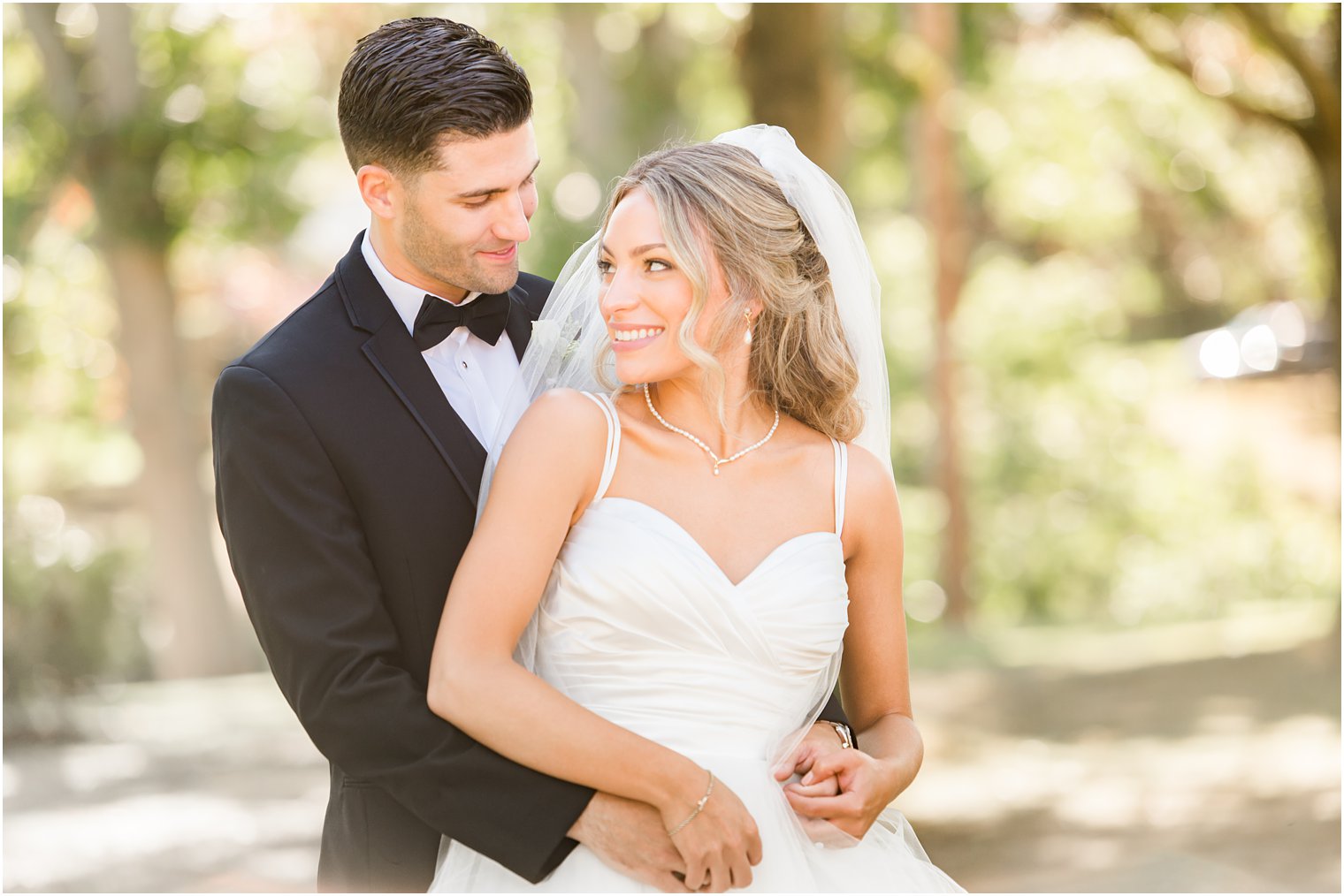 groom hugs bride from behind during NJ wedding photos