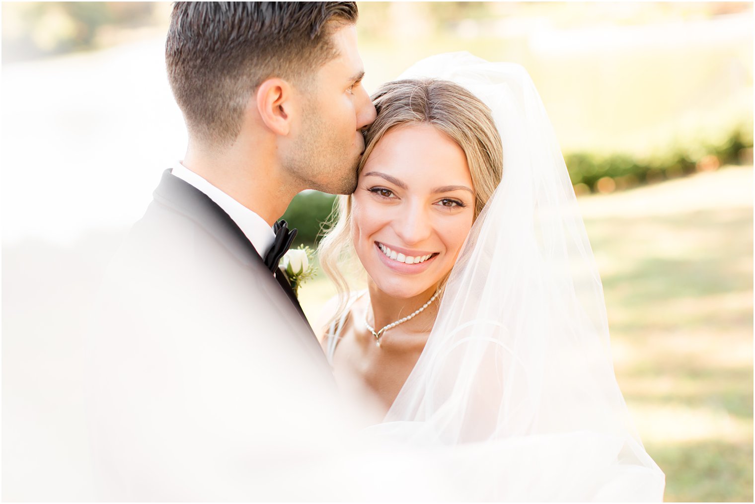 groom kisses bride's head during NJ wedding photos