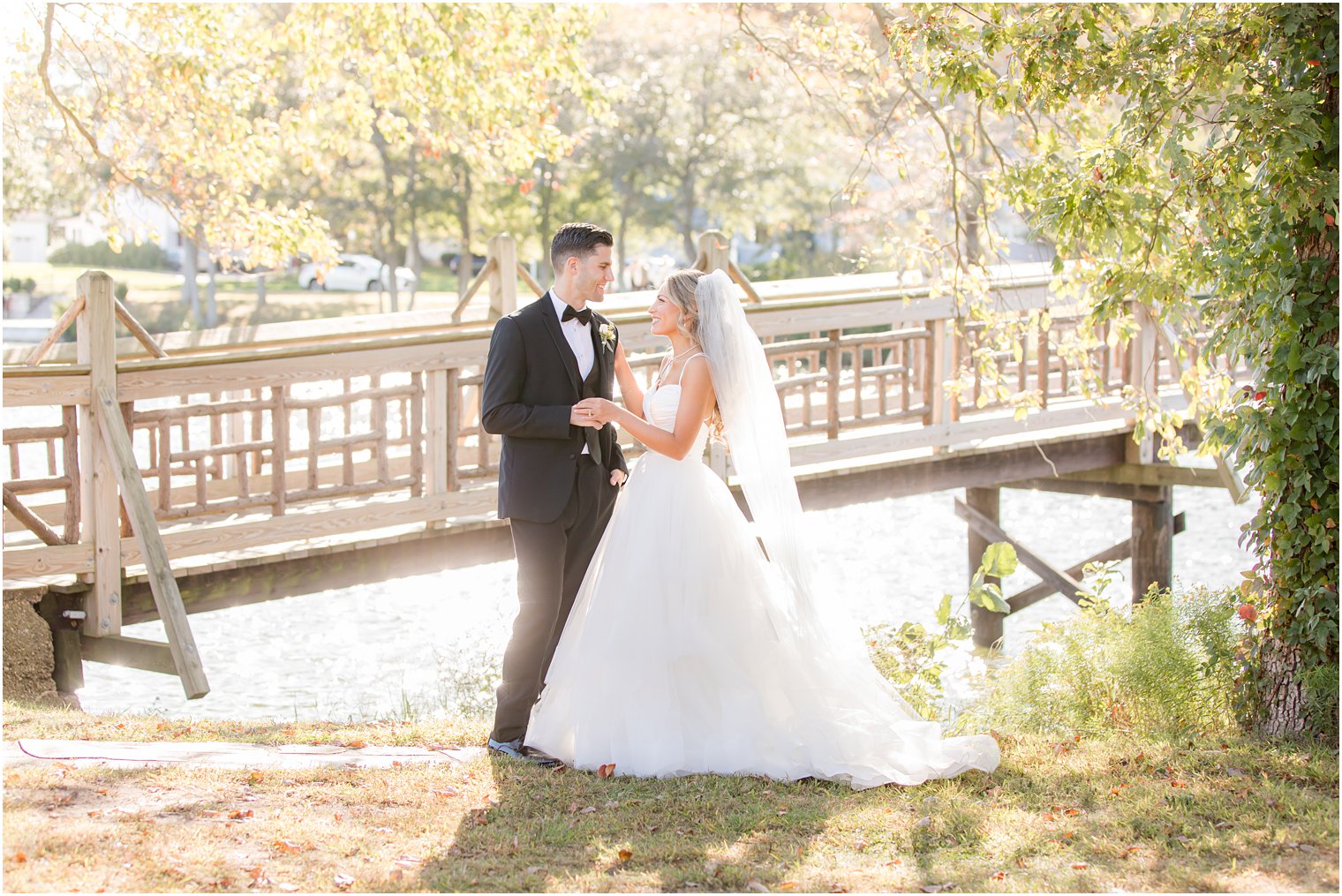 newlyweds pose by wooden bridge in Spring Lake NJ park
