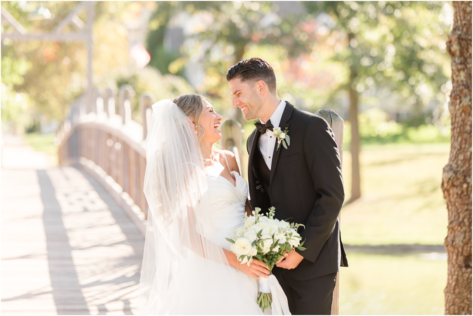 bride and groom smile together by wooden bridge in Spring Lake NJ