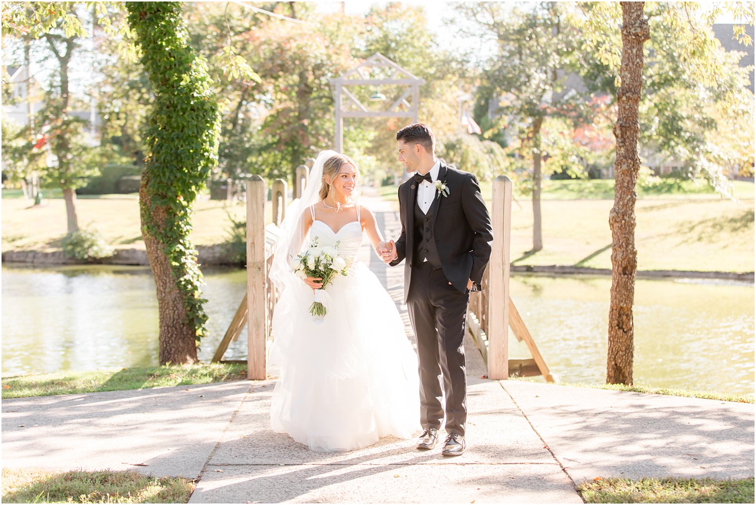 newlyweds walk over wooden bridge in Spring Lake NJ