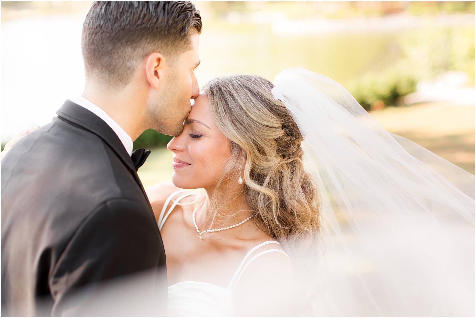 groom kisses bride's forehead during NJ wedding photos