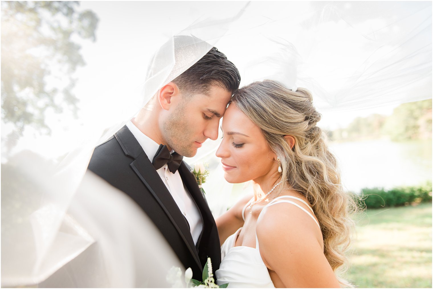 bride and groom pose under bride's veil during portraits