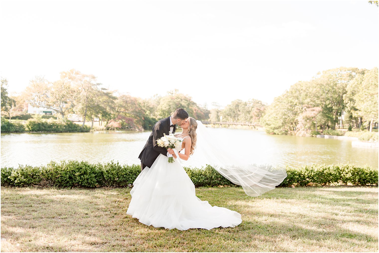 groom kisses bride with veil floating behind her during portraits in NJ