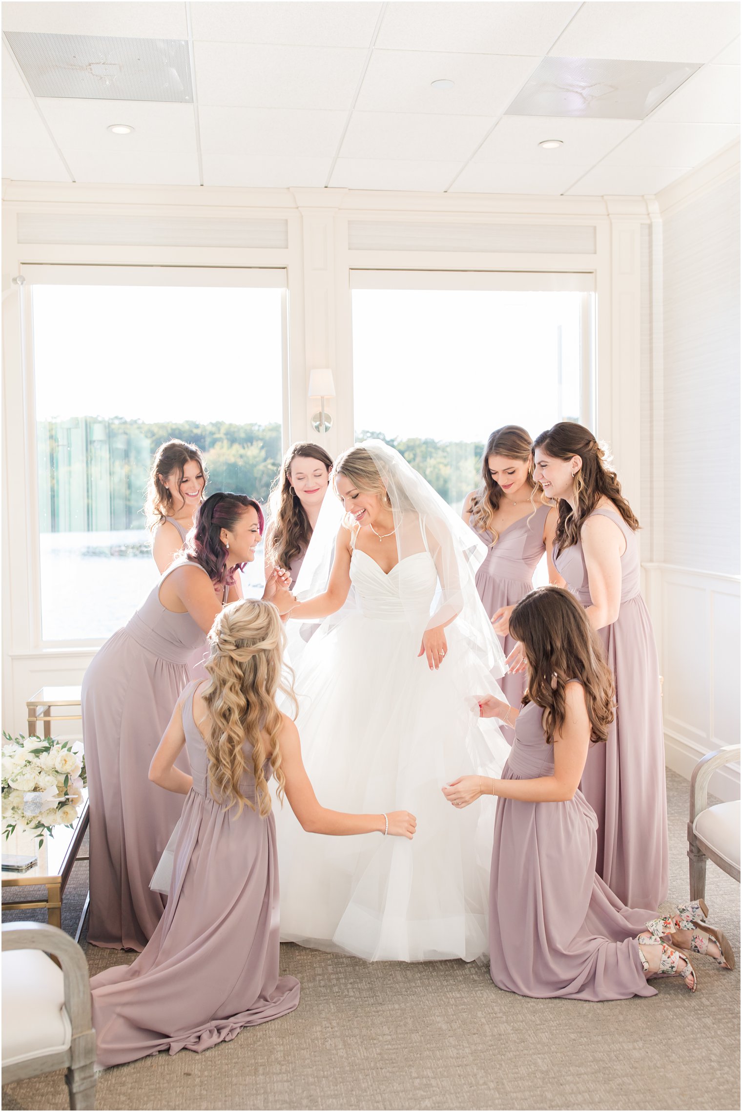 bridesmaids in mauve dresses help bride with wedding dress at the Mill Lakeside Manor