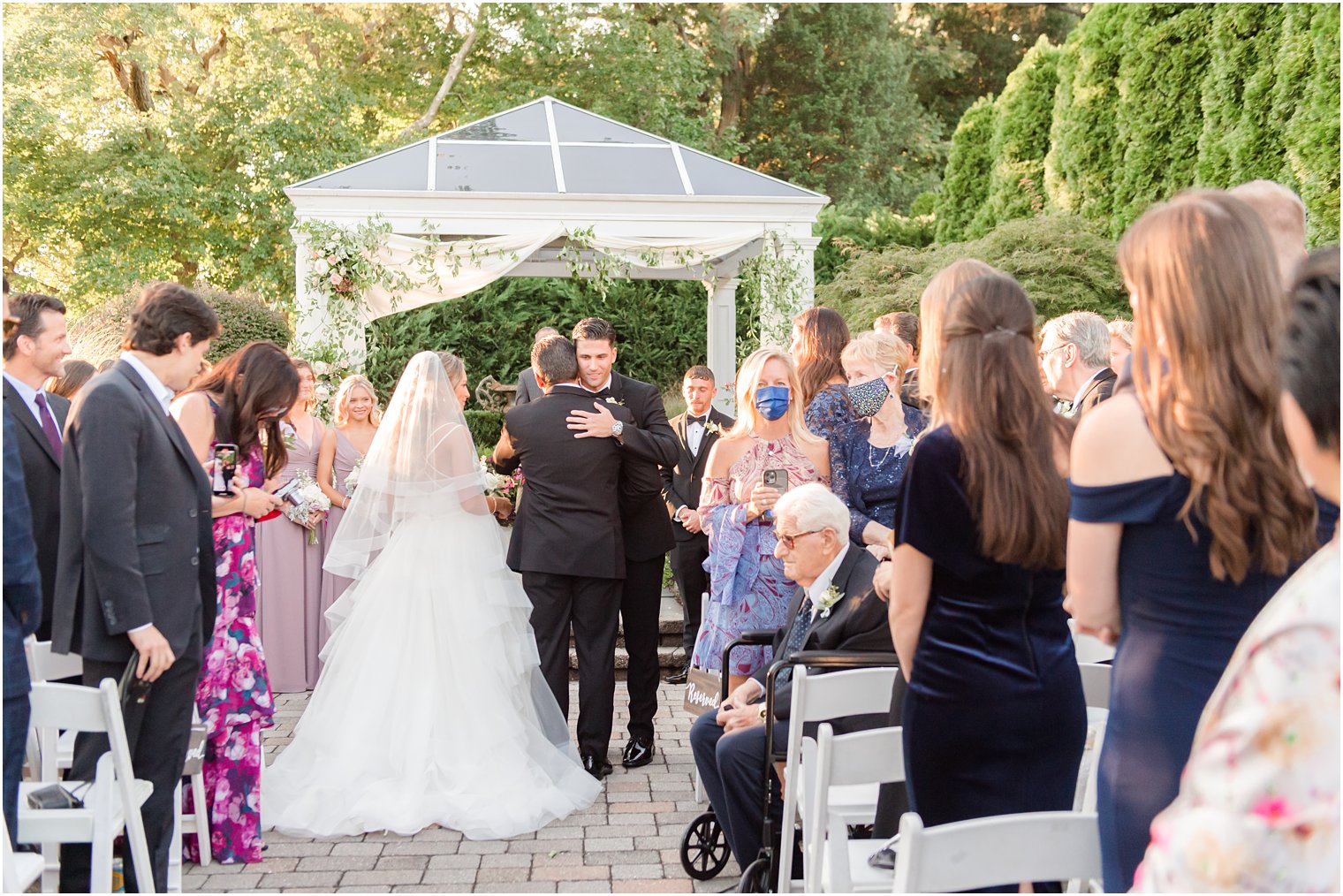 bride walks down aisle with dad hugging groom