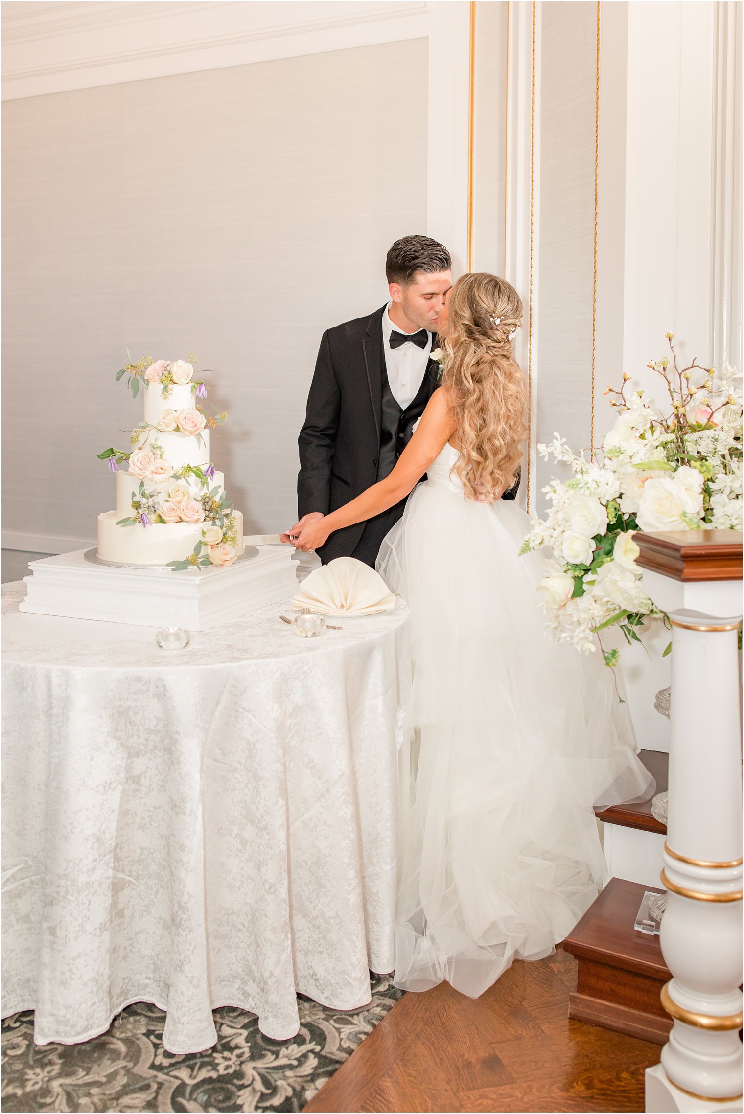 bride and groom kiss by wedding cake at Spring Lake NJ