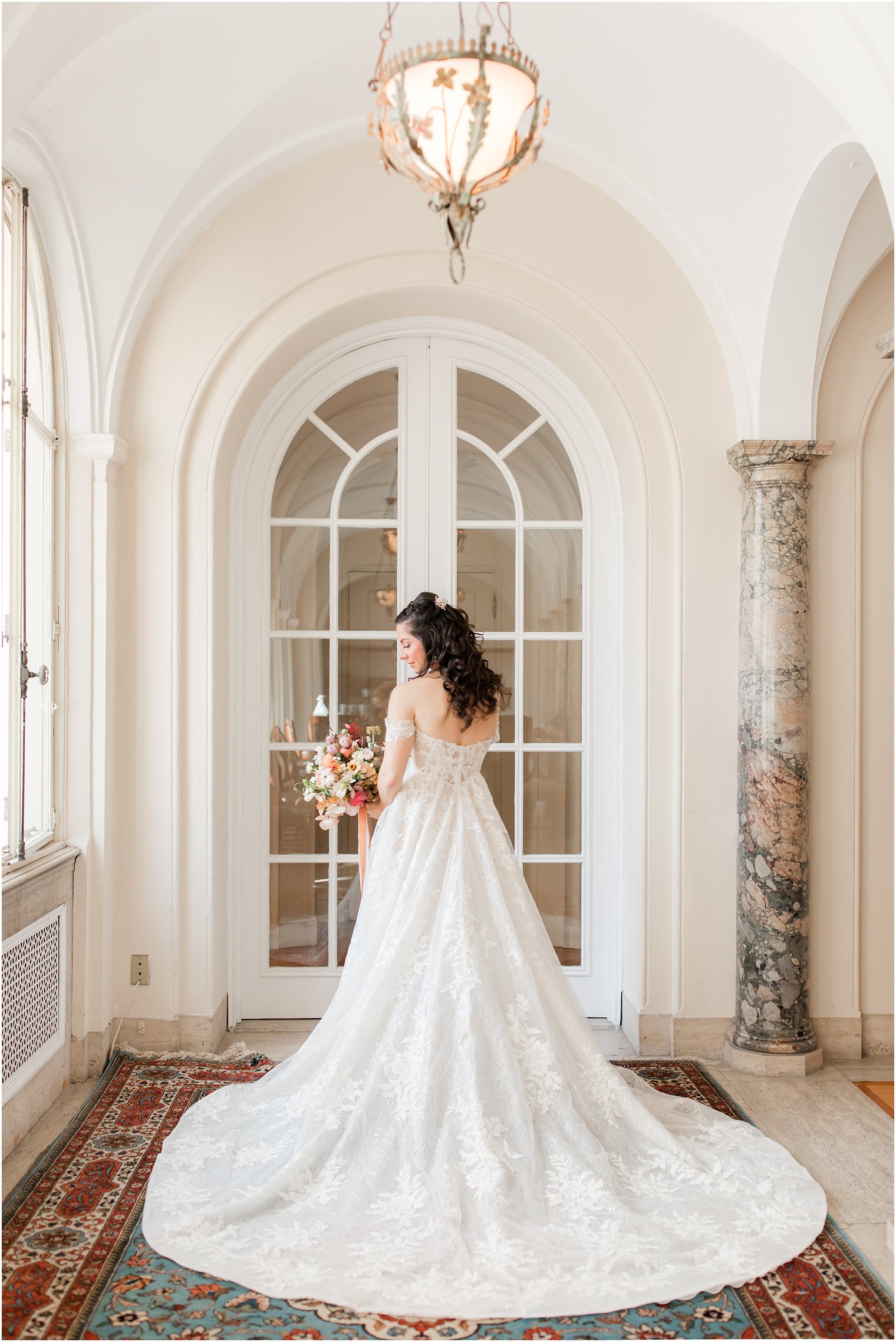 bride poses in hallway looking over shoulder during Village Club of Sands Point wedding portraits