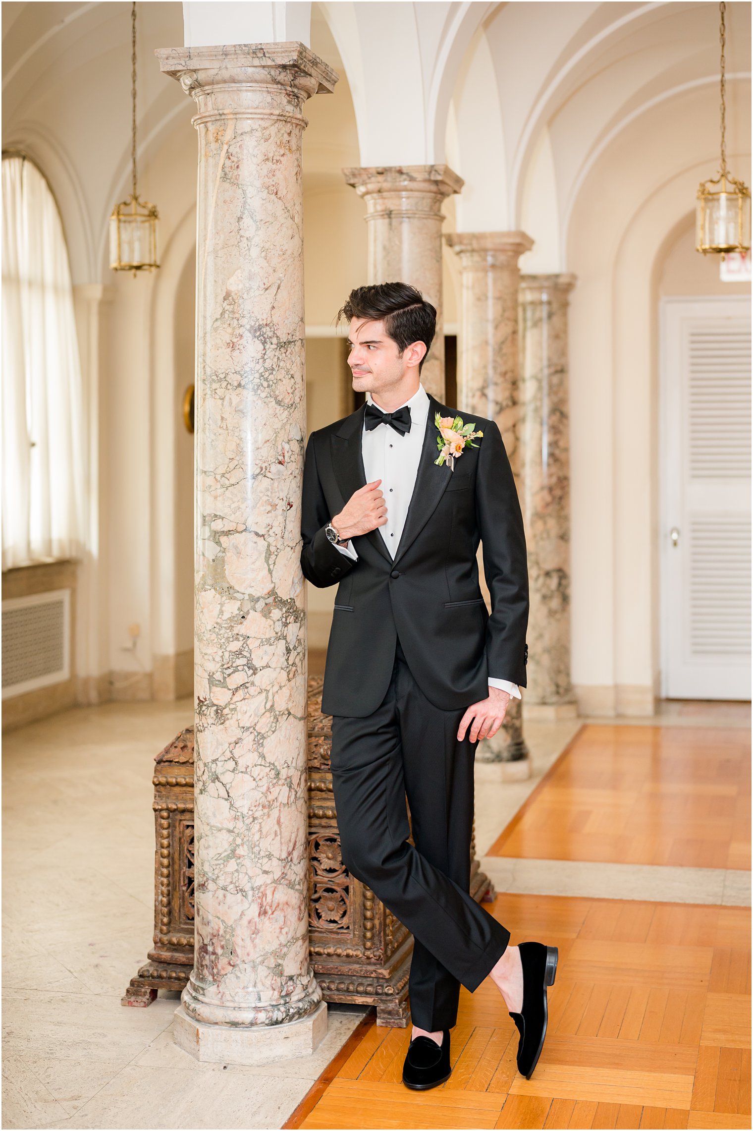 groom leans against marble pillar at Village Club of Sands Point