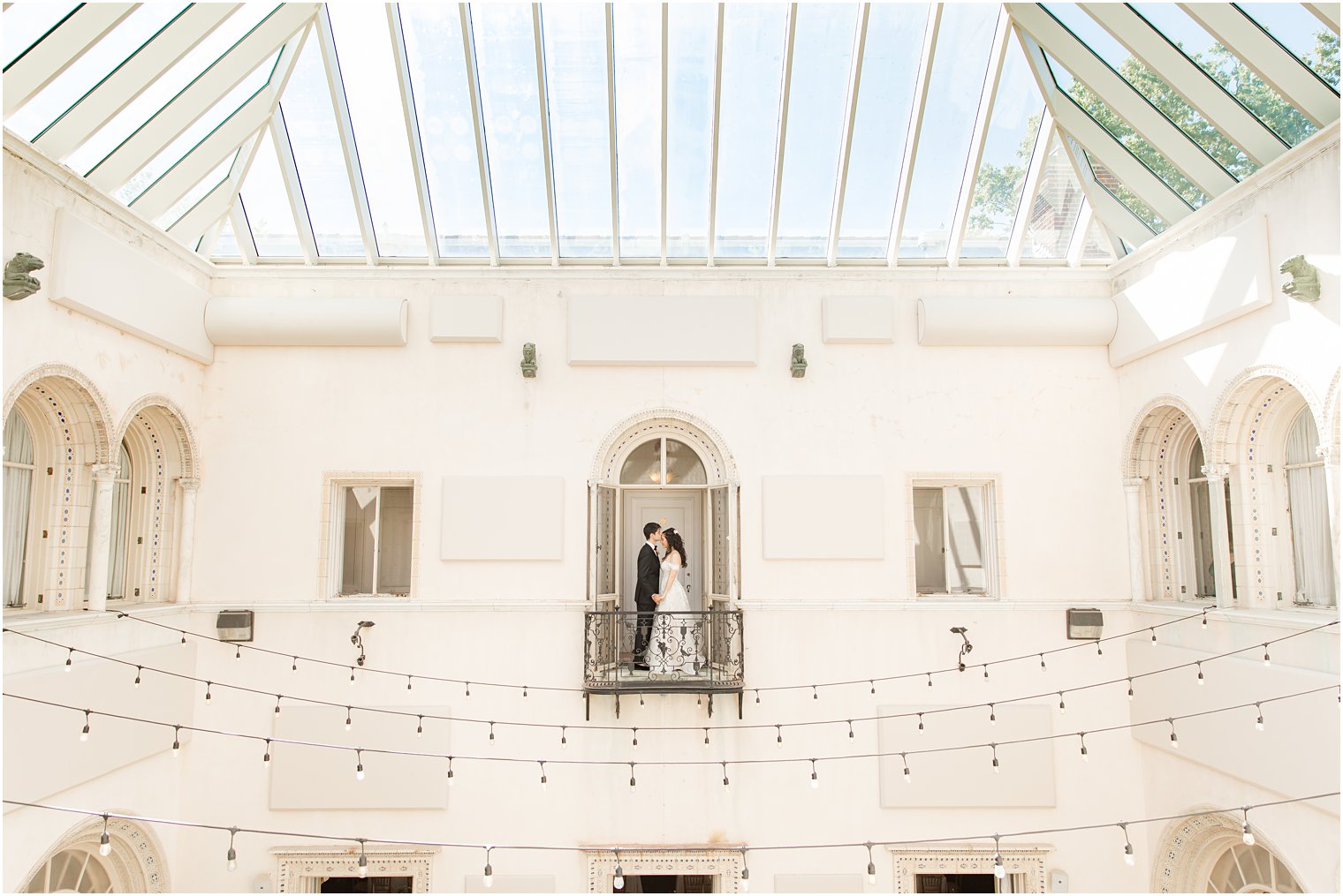 newlyweds pose on balcony over atrium at the Village Club of Sands Point