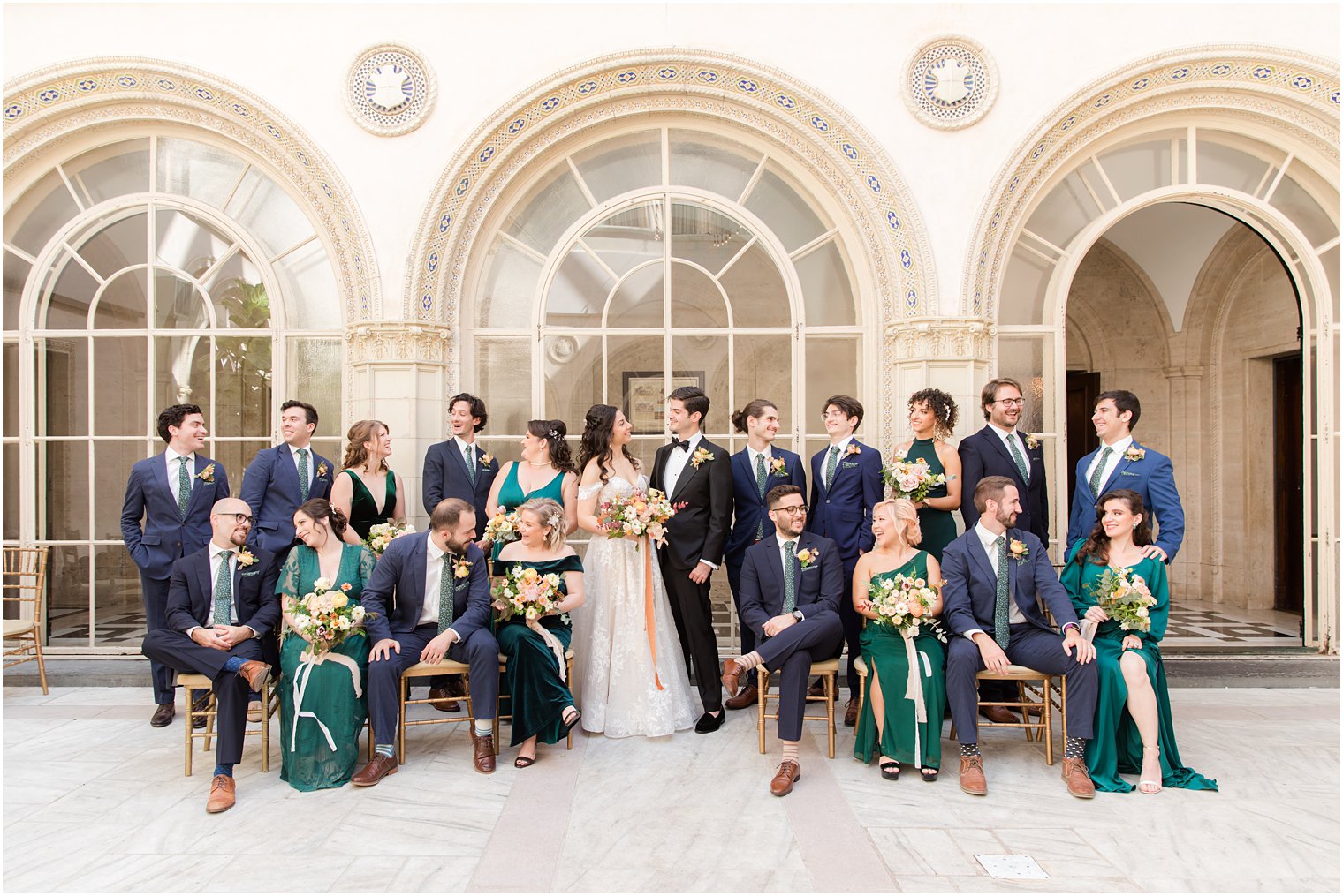 bride and groom pose with wedding party in navy and emerald green