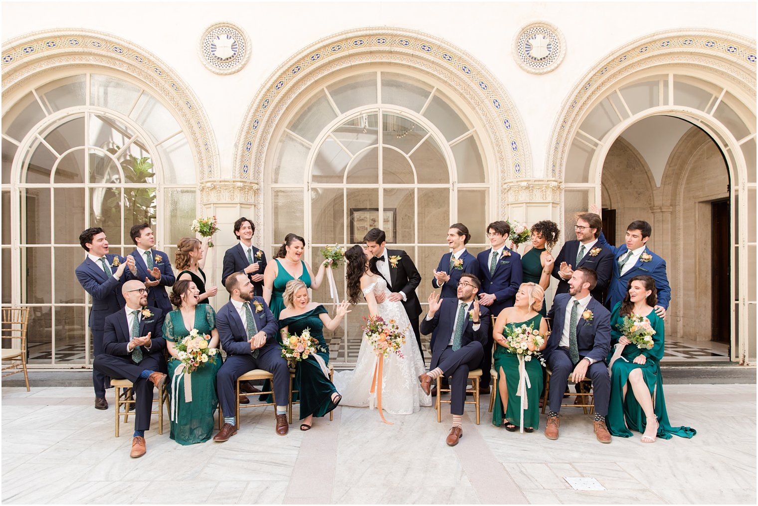 bride and groom pose with wedding party in navy and green