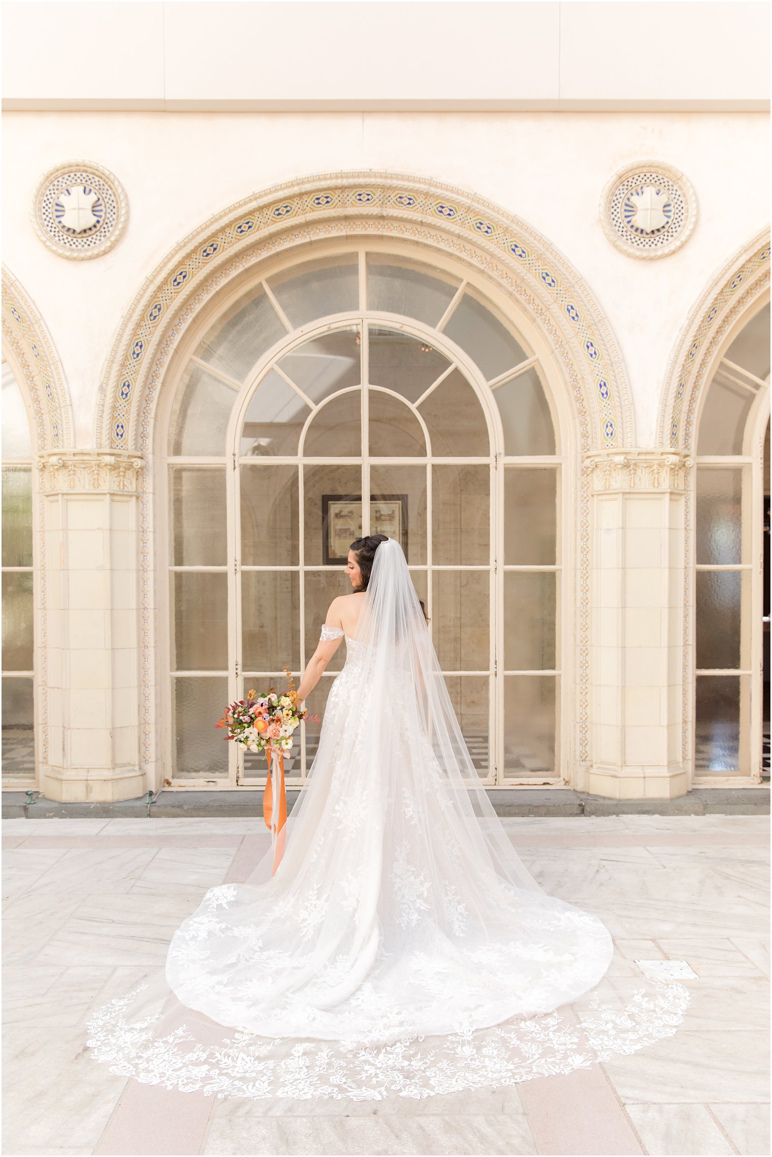 bride looks over shoulder holding bouquet with veil draped 