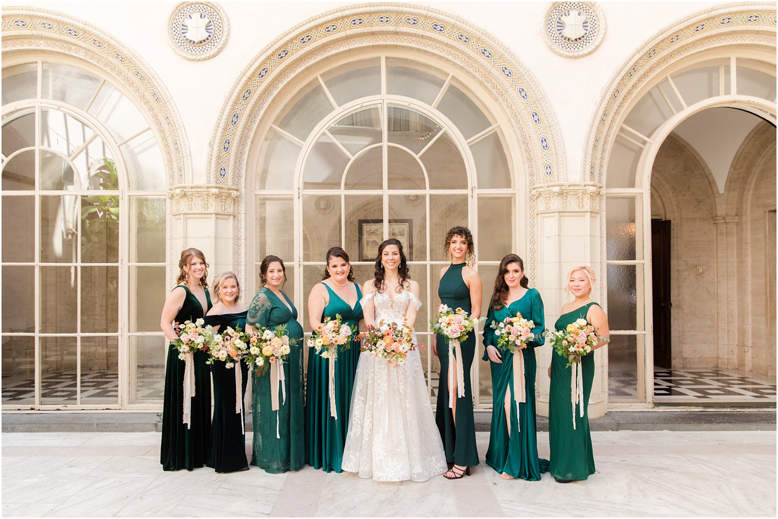 bride poses with bridesmaids in emerald green gowns