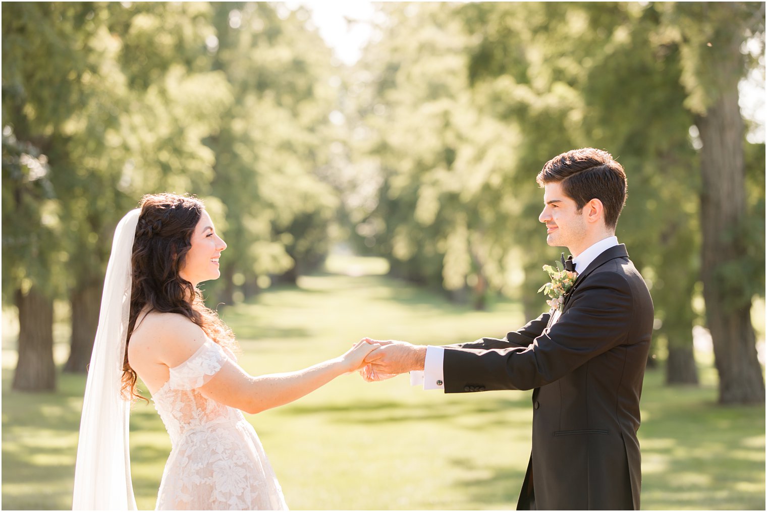 bride and groom hold hands looking at each other during New York wedding portraits