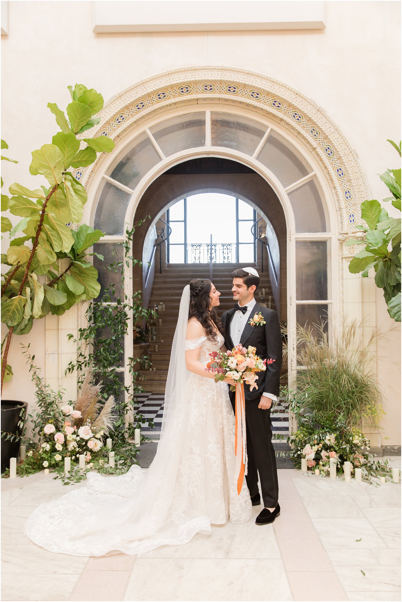 bride and groom pose by staircase with candles 