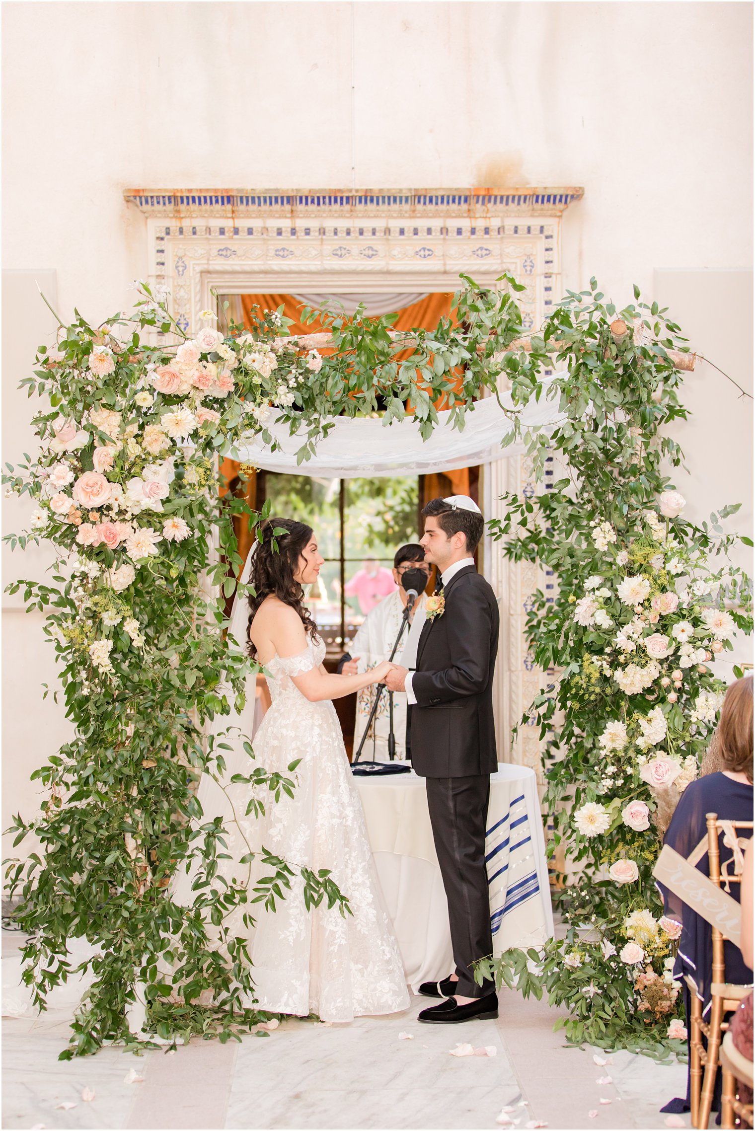 bride and groom exchange vows during flower covered chuppah