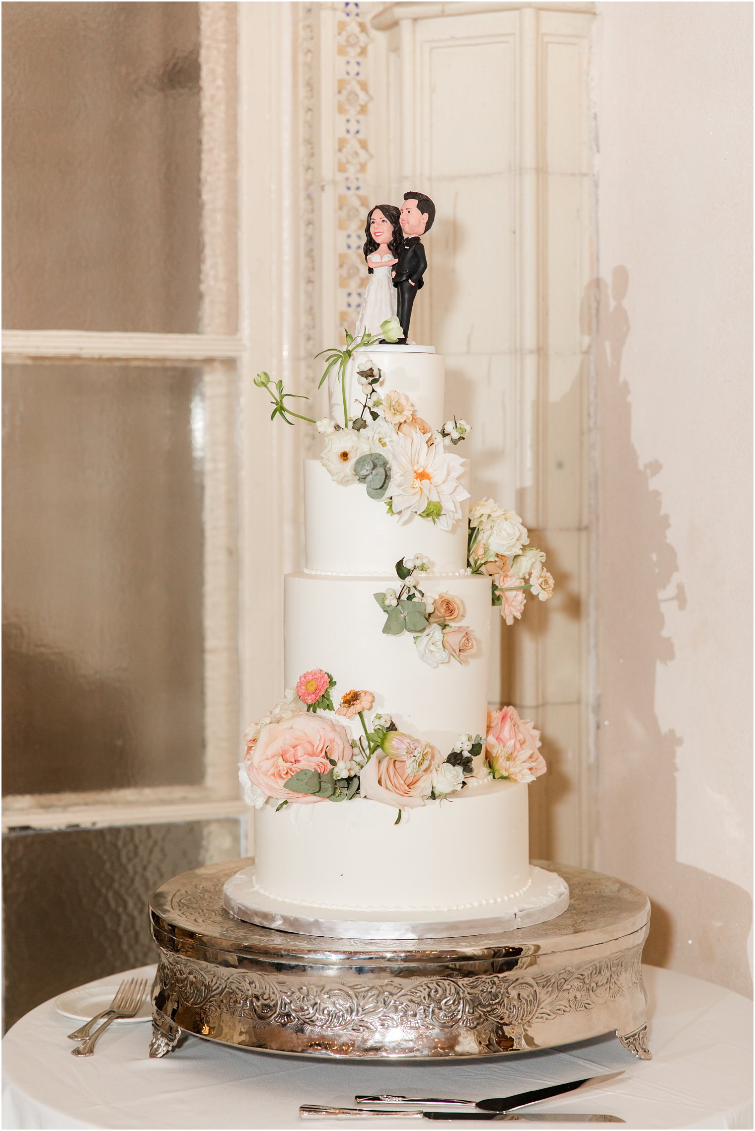 tiered wedding cake with bobble heads of bride and groom on top