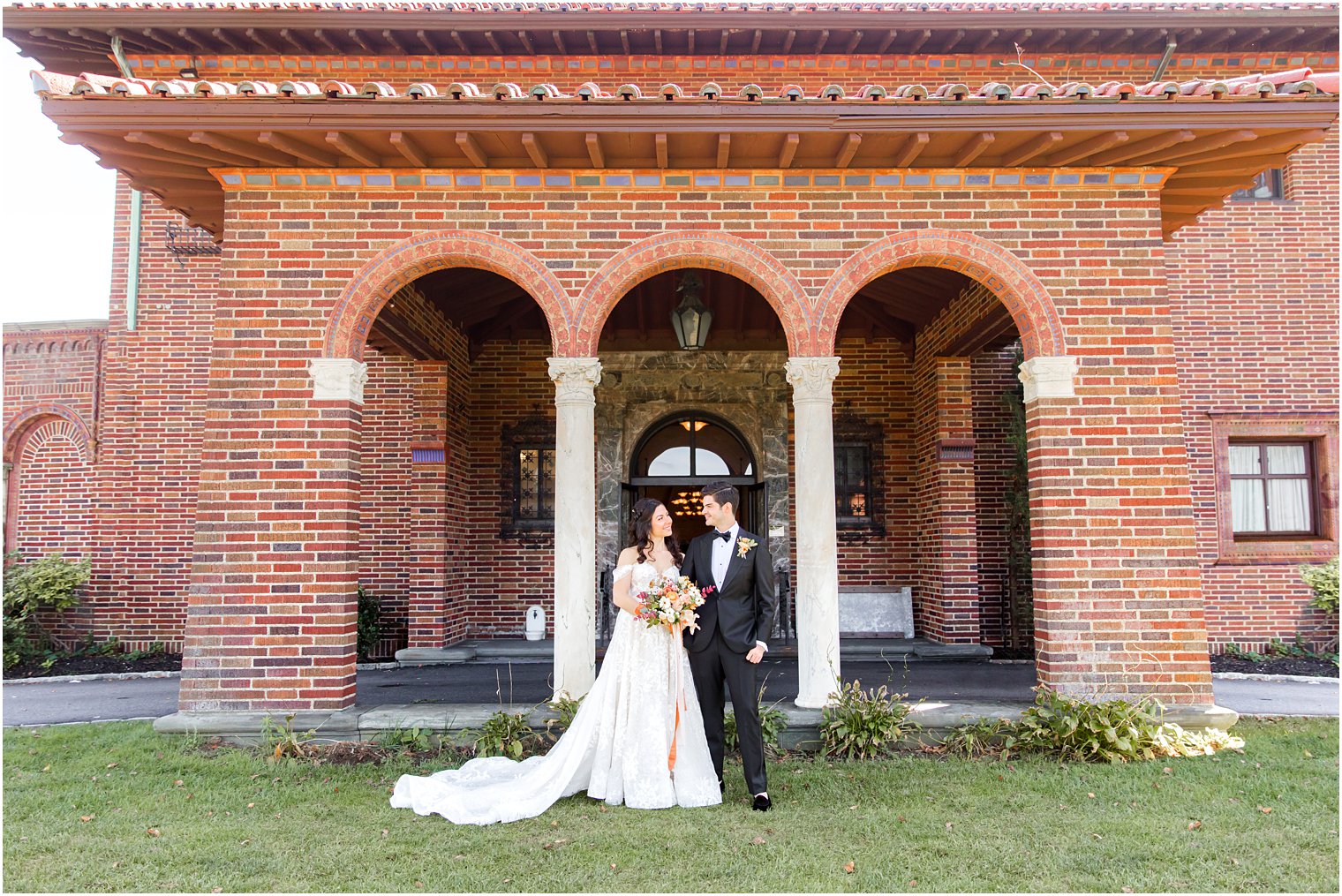 bride and groom pose outside brick villa at the Village Club of Sands Point