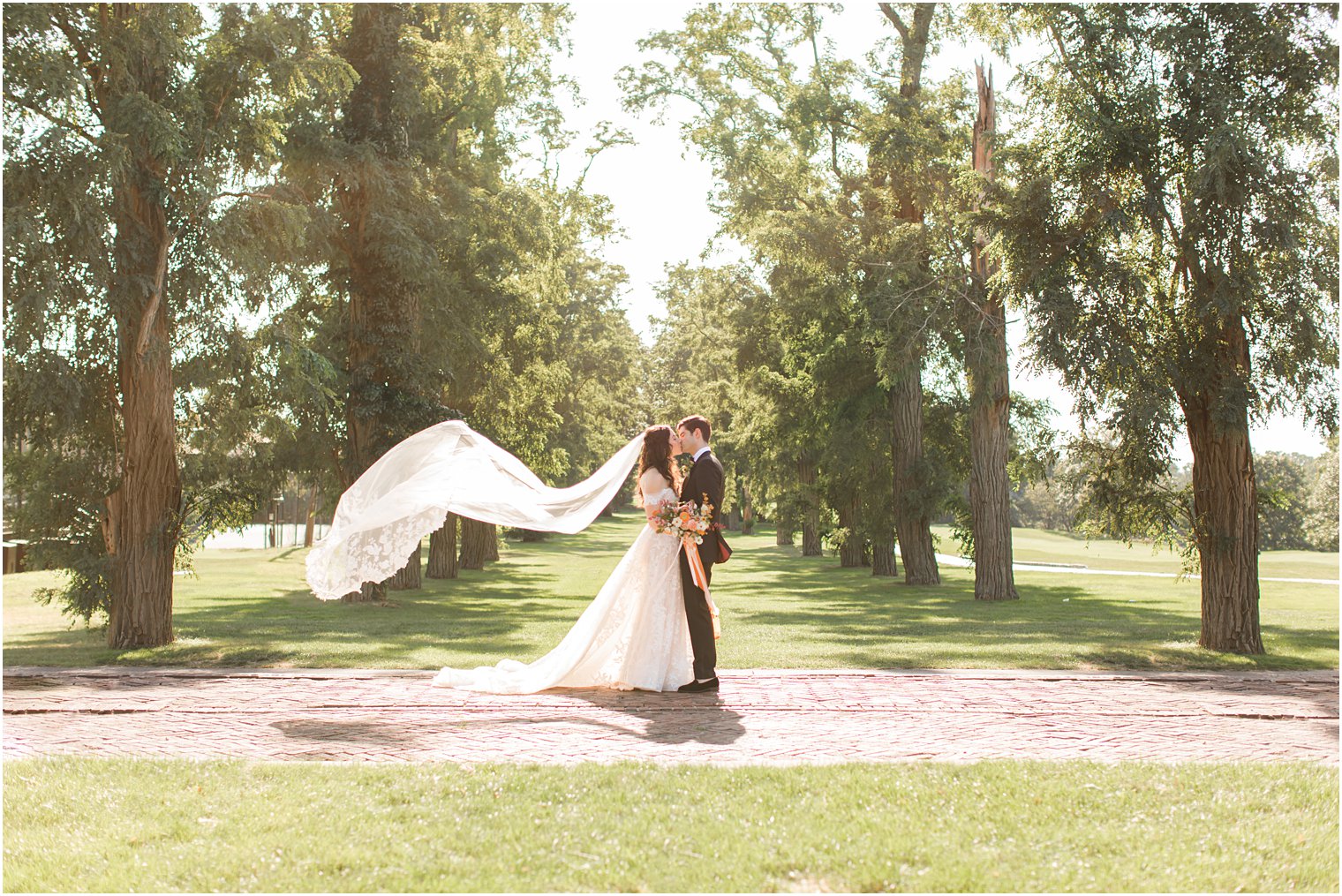 bride and groom kiss while bride's veil floats behind them