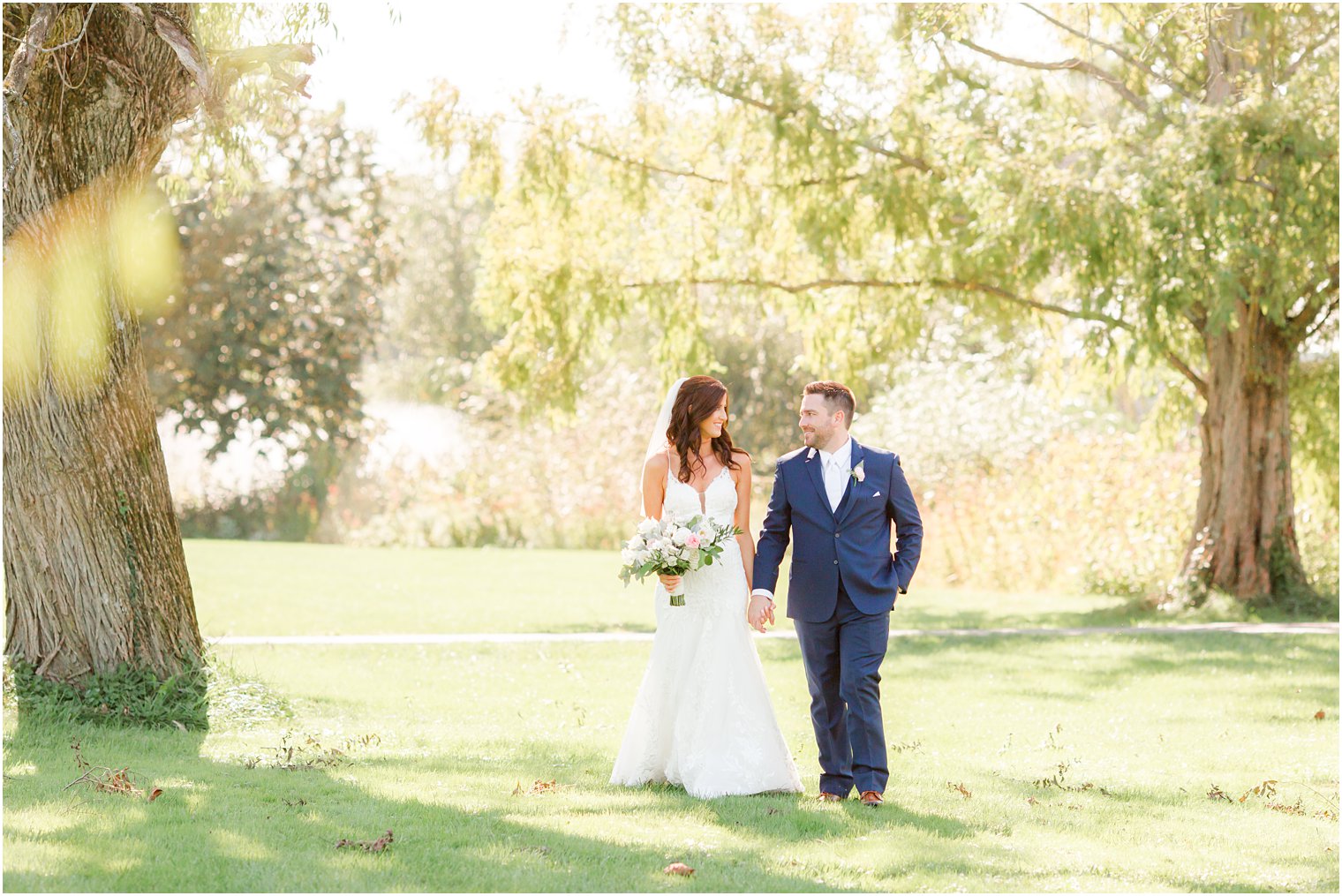 bride and groom hold hands walking under tree in Princeton NJ 