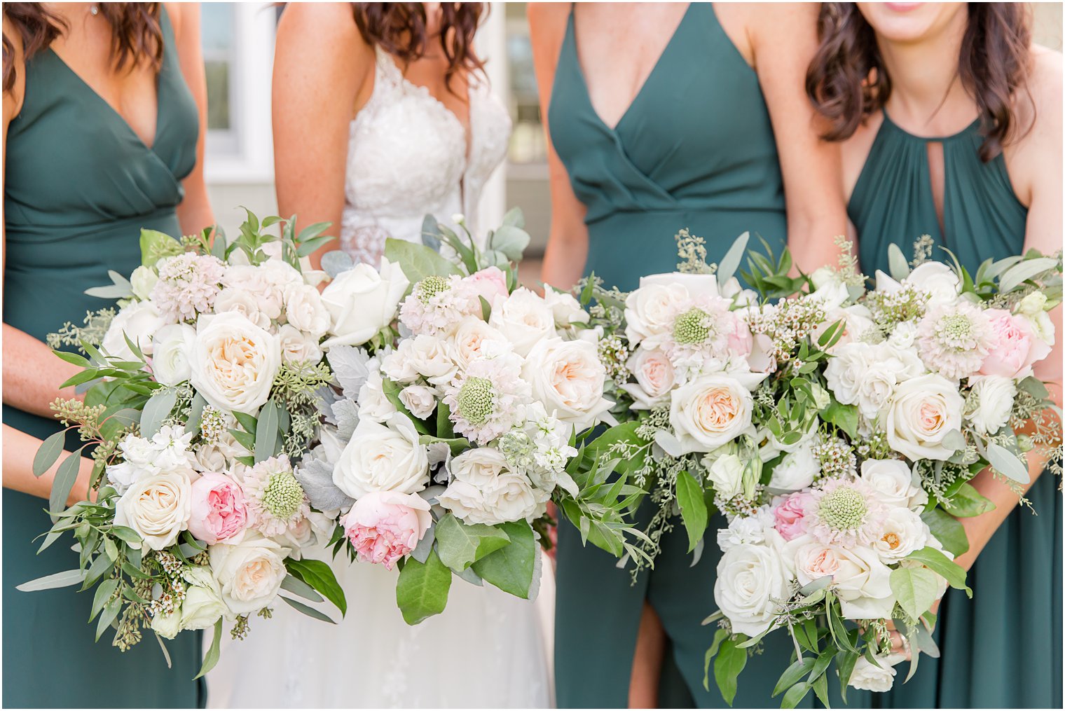 bride and bridesmaids hold pastel bouquets during wedding portraits at the Chauncey Hotel