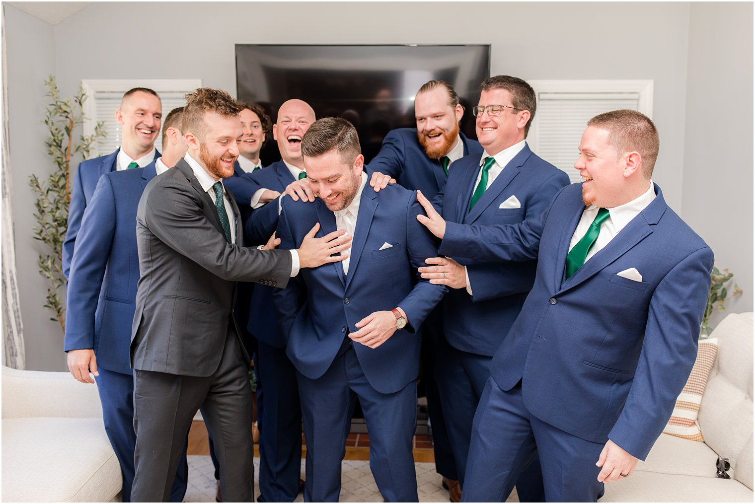 groomsmen in navy suits with emerald ties pat groom on the back 