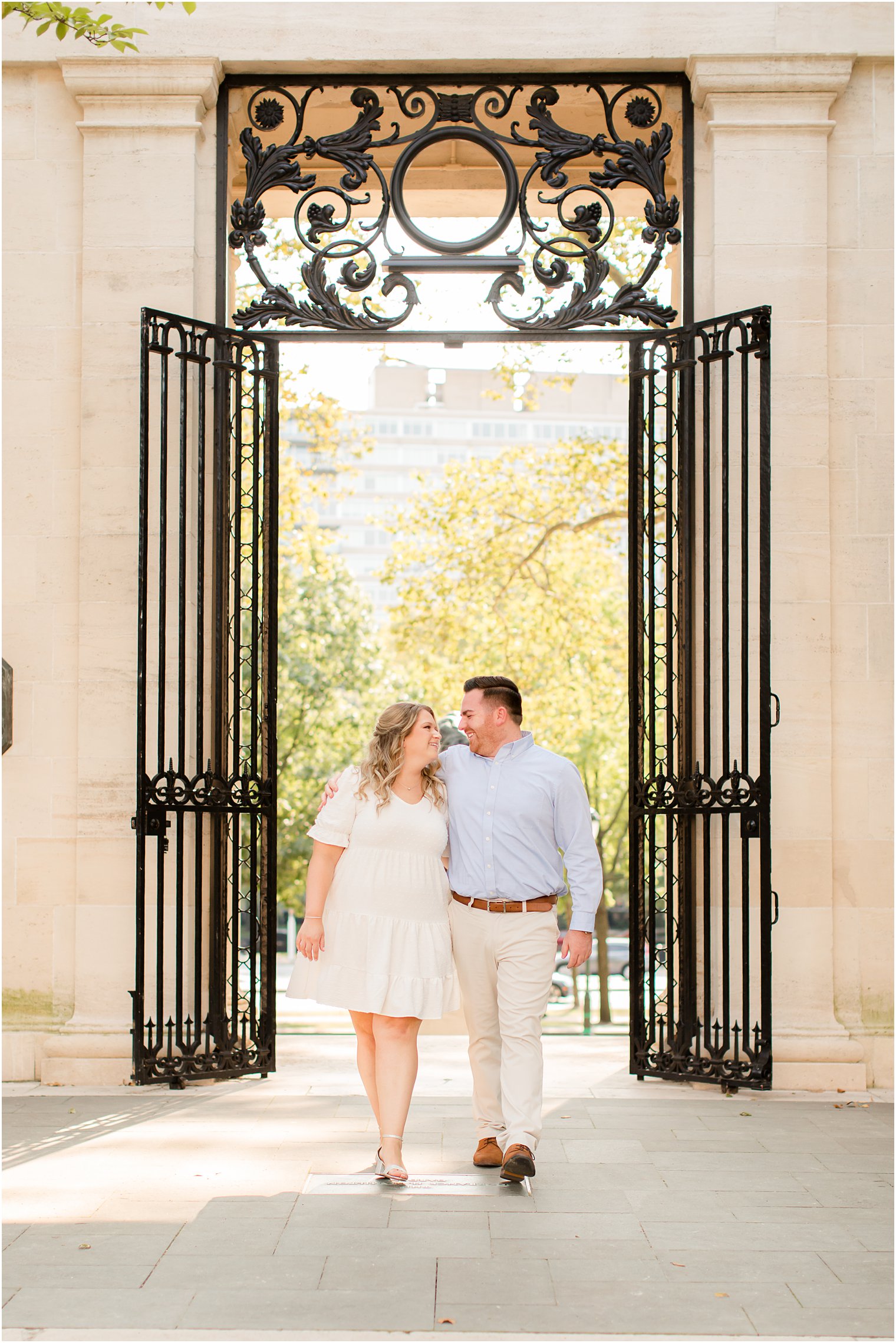 bride and groom look at each other walking through wrought iron gate during Rodin Museum engagement session
