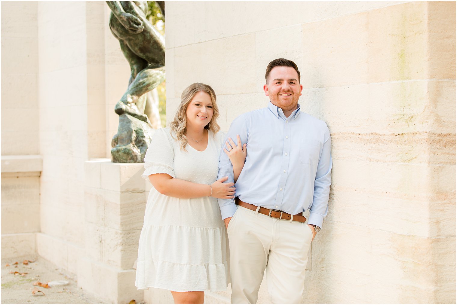 bride holds groom's arm leaning against column during Rodin Museum engagement session