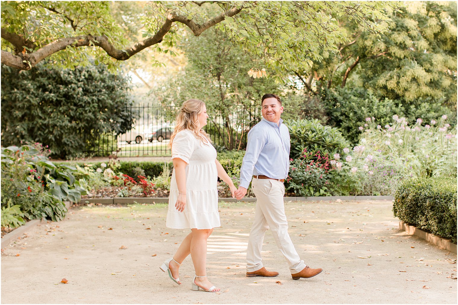 couple holds hands walking through Rodin Museum engagement session during the spring