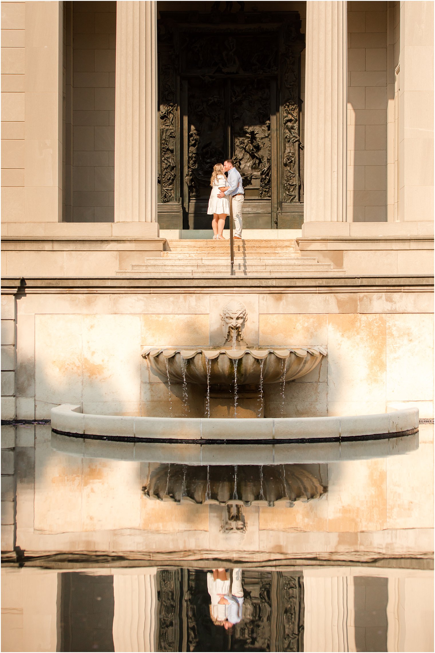 bride and groom stand on steps by fountain in Rodin Museum