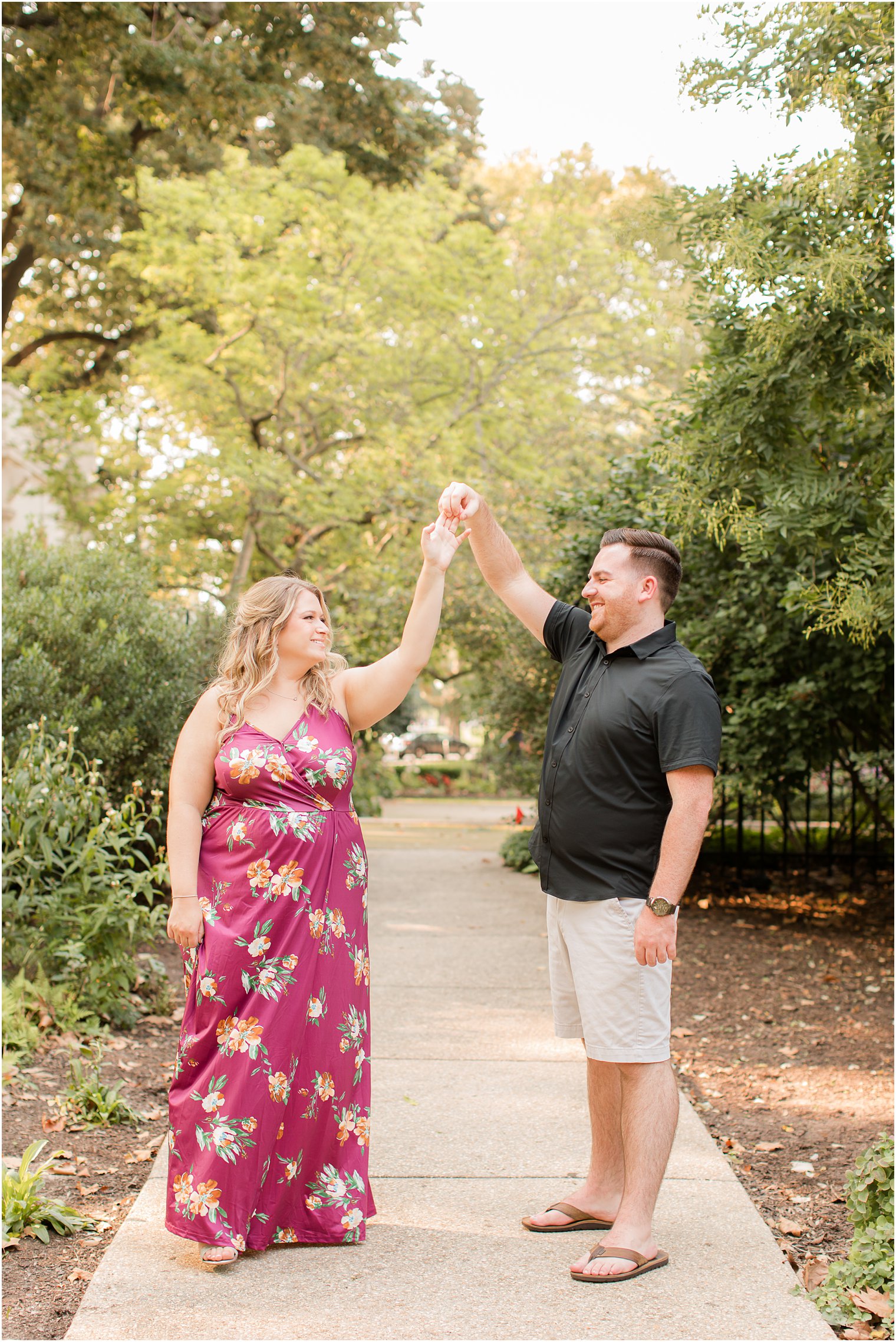 groom twirls bride during Rodin Museum engagement session in the spring