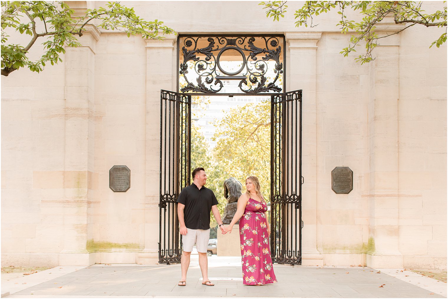 bride and groom hold hands outside wrought iron gate at the Rodin Museum 