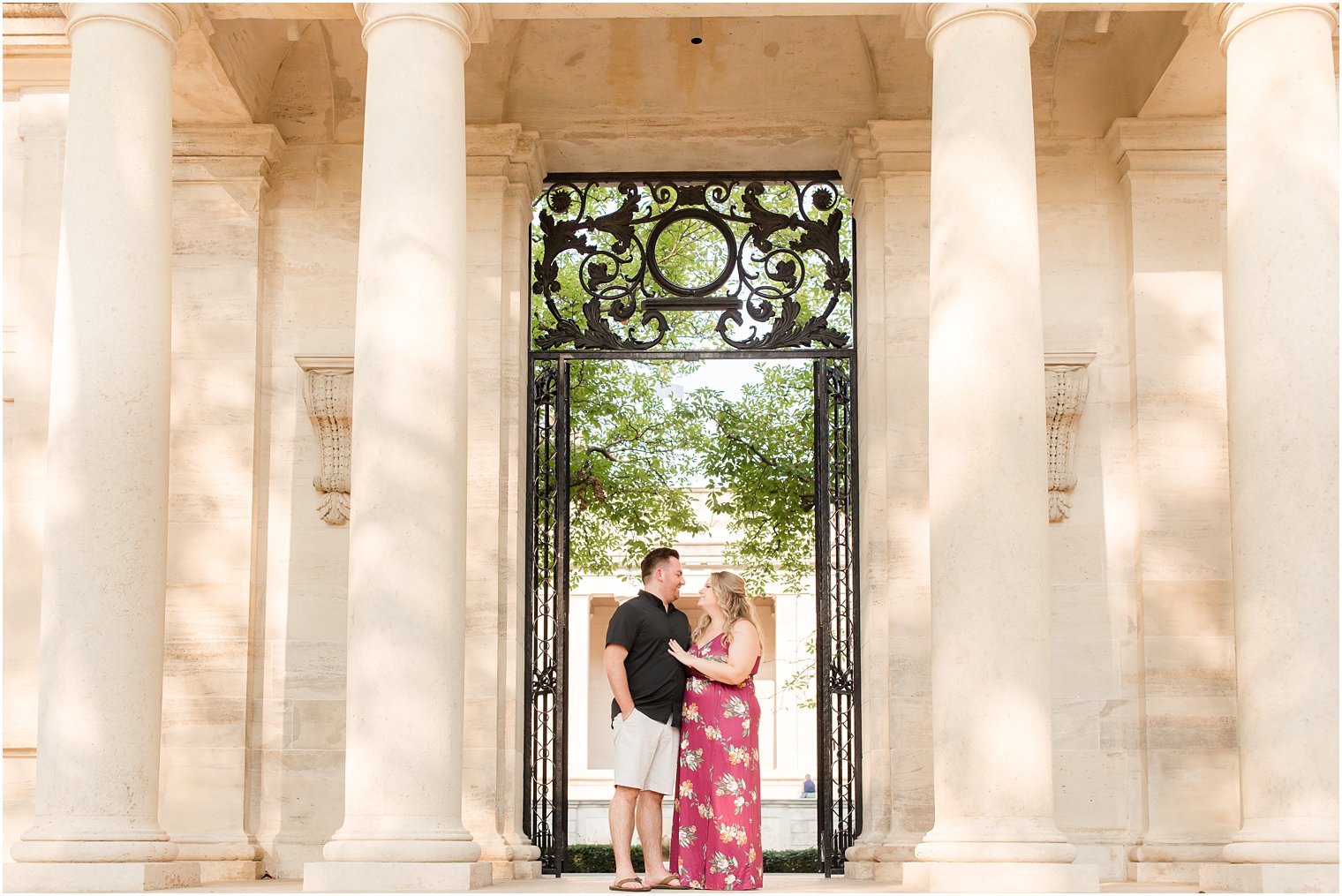 engaged couple stands by gate outside the Rodin Museum