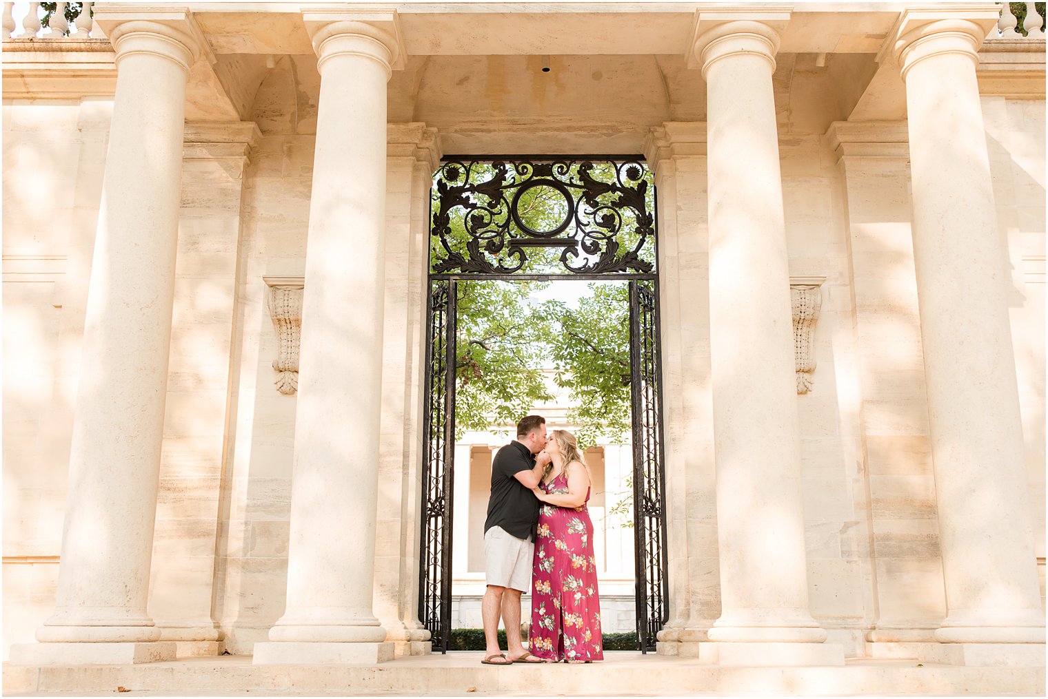 couple kisses by wrought iron gate during Rodin Museum engagement session
