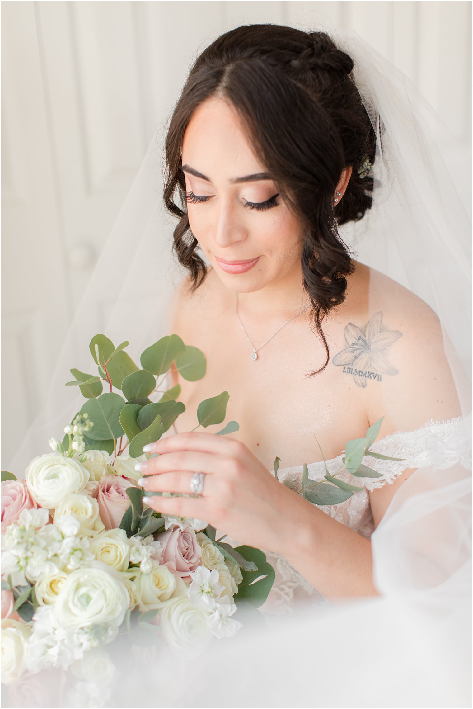 bride looks down at bouquet of pink and ivory flowers 