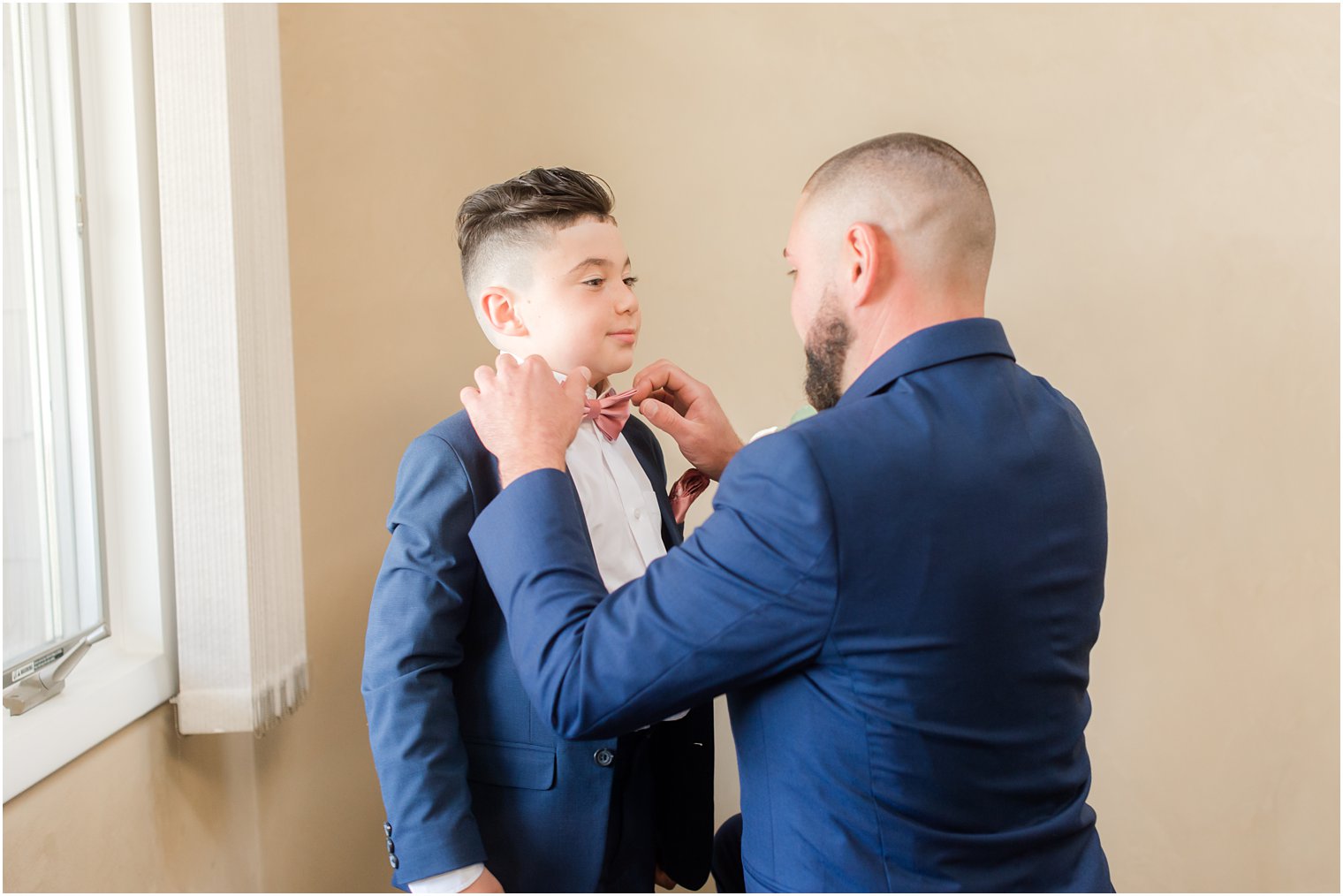 groom adjusts son's pink bowtie before NJ wedding