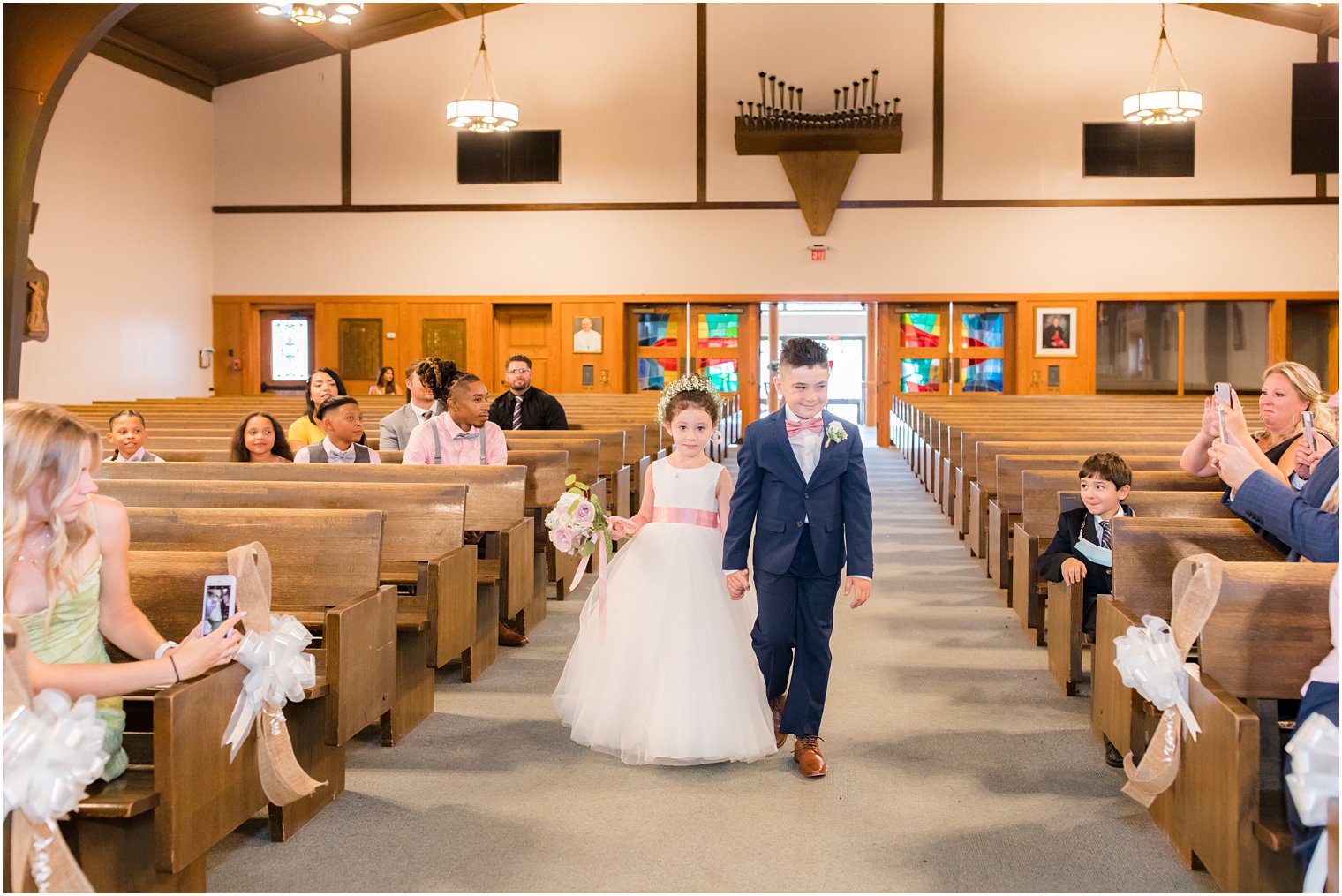 bride and groom's children walk down aisle as flower girl and ring bearer for traditional wedding ceremony at Saint Matthew the Apostle church