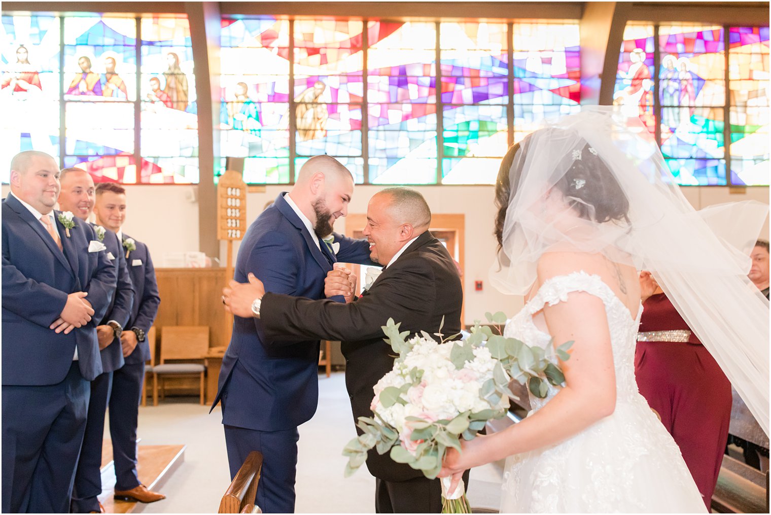 bride's father hugs groom before traditional wedding ceremony at Saint Matthew the Apostle church